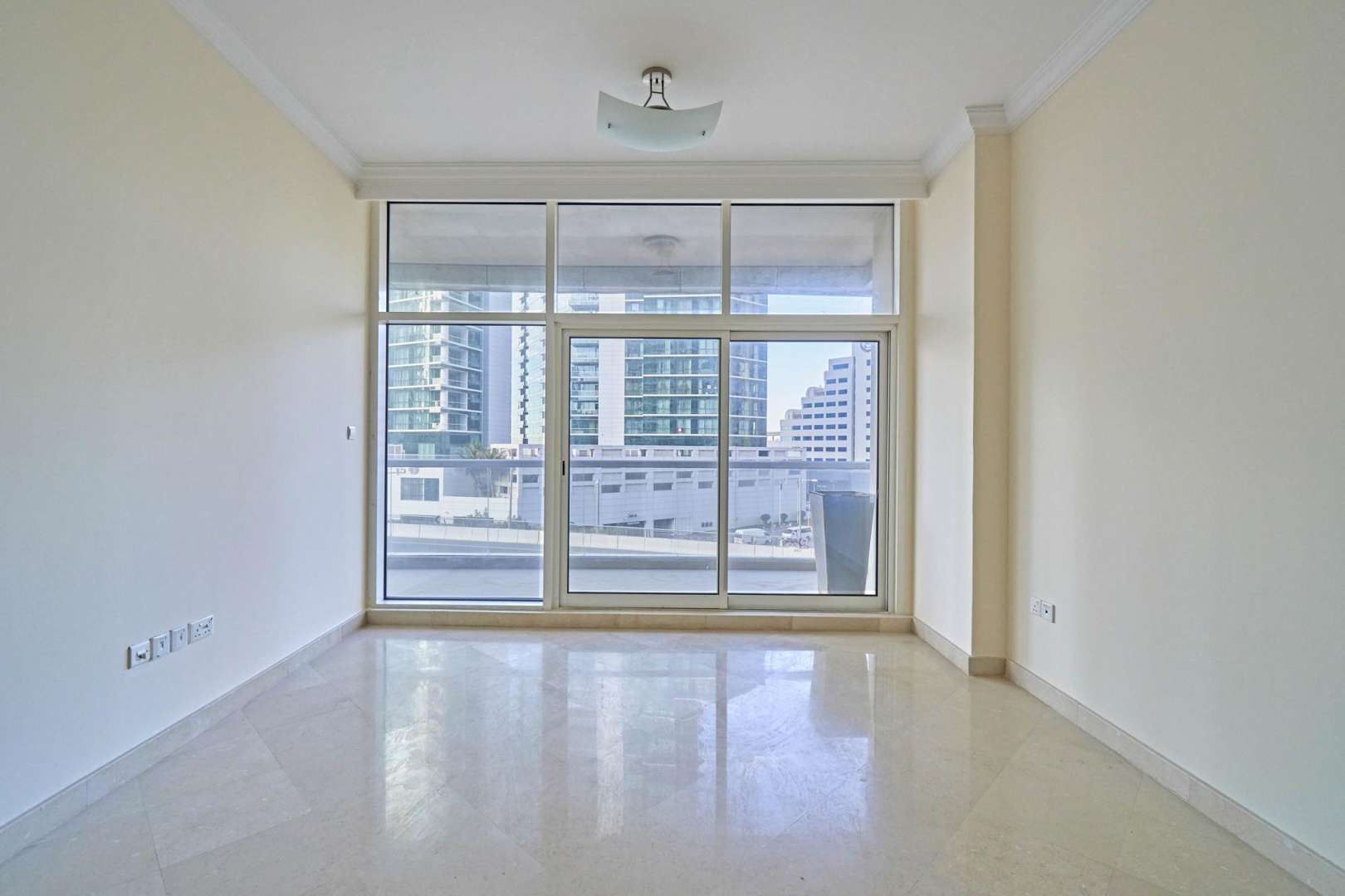 "Modern high-rise apartment building in Dorra Bay, Dubai Marina for rent, exterior view.",Empty living room with large windows in Dorra Bay apartment, Dubai Marina