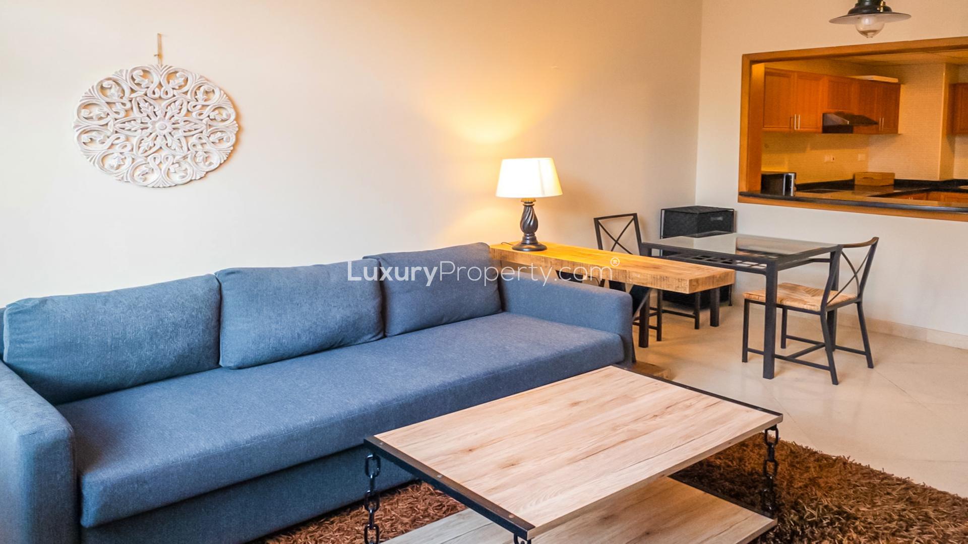 Contemporary living room in one-bedroom Dubai Marina apartment, featuring cozy sofa and dining area