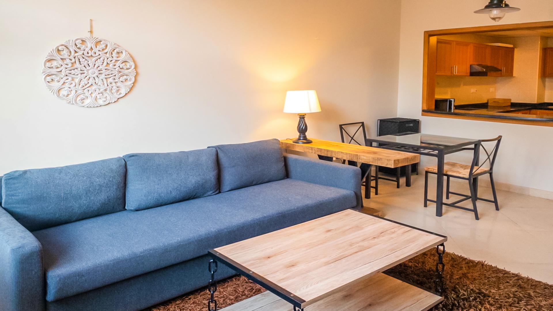 Contemporary living room in one-bedroom Dubai Marina apartment, featuring cozy sofa and dining area