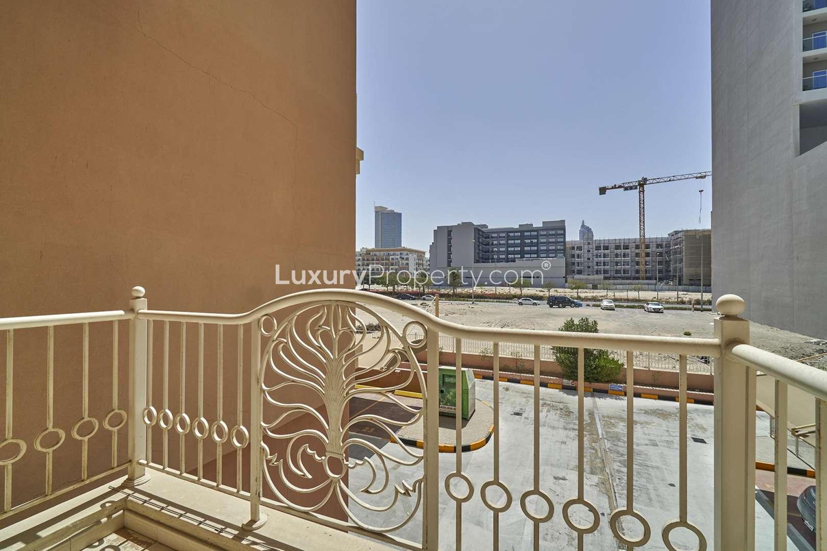 Empty bright room with tiled floor and balcony view in Emirates Garden apartment, JVC