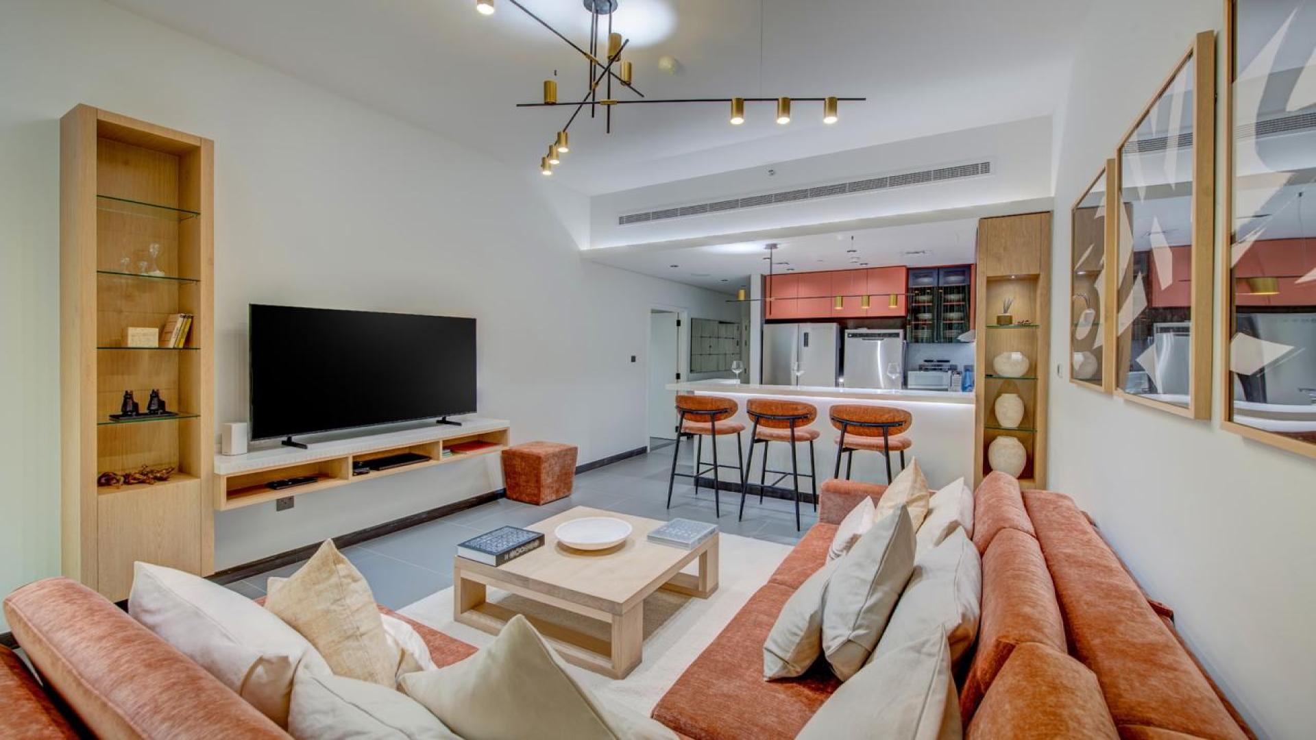 Furnished kitchen and living area in JLT apartment with large windows and modern decor