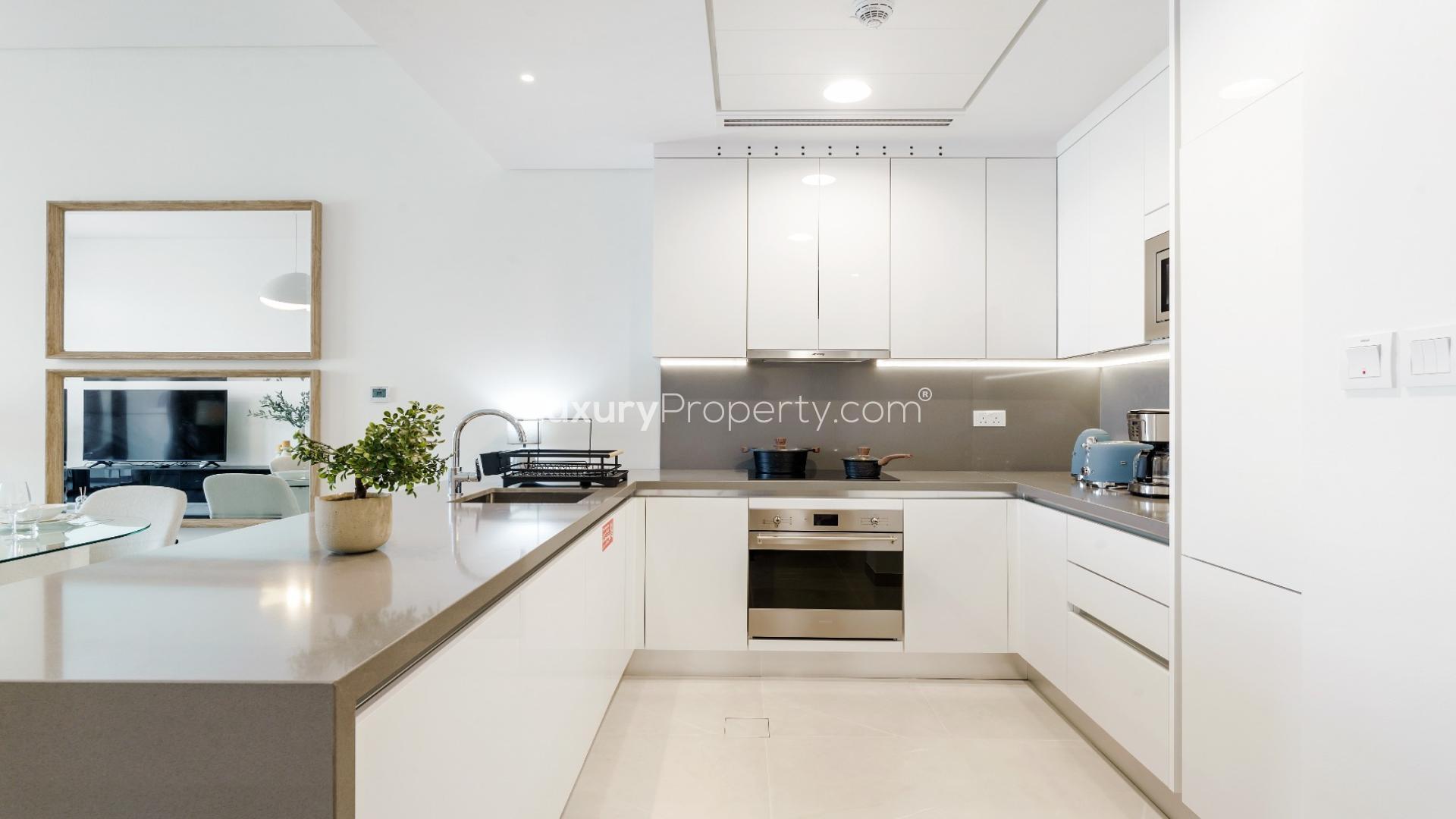 Modern kitchen in Canal Front Residences apartment, Al Wasl, with sleek white cabinetry