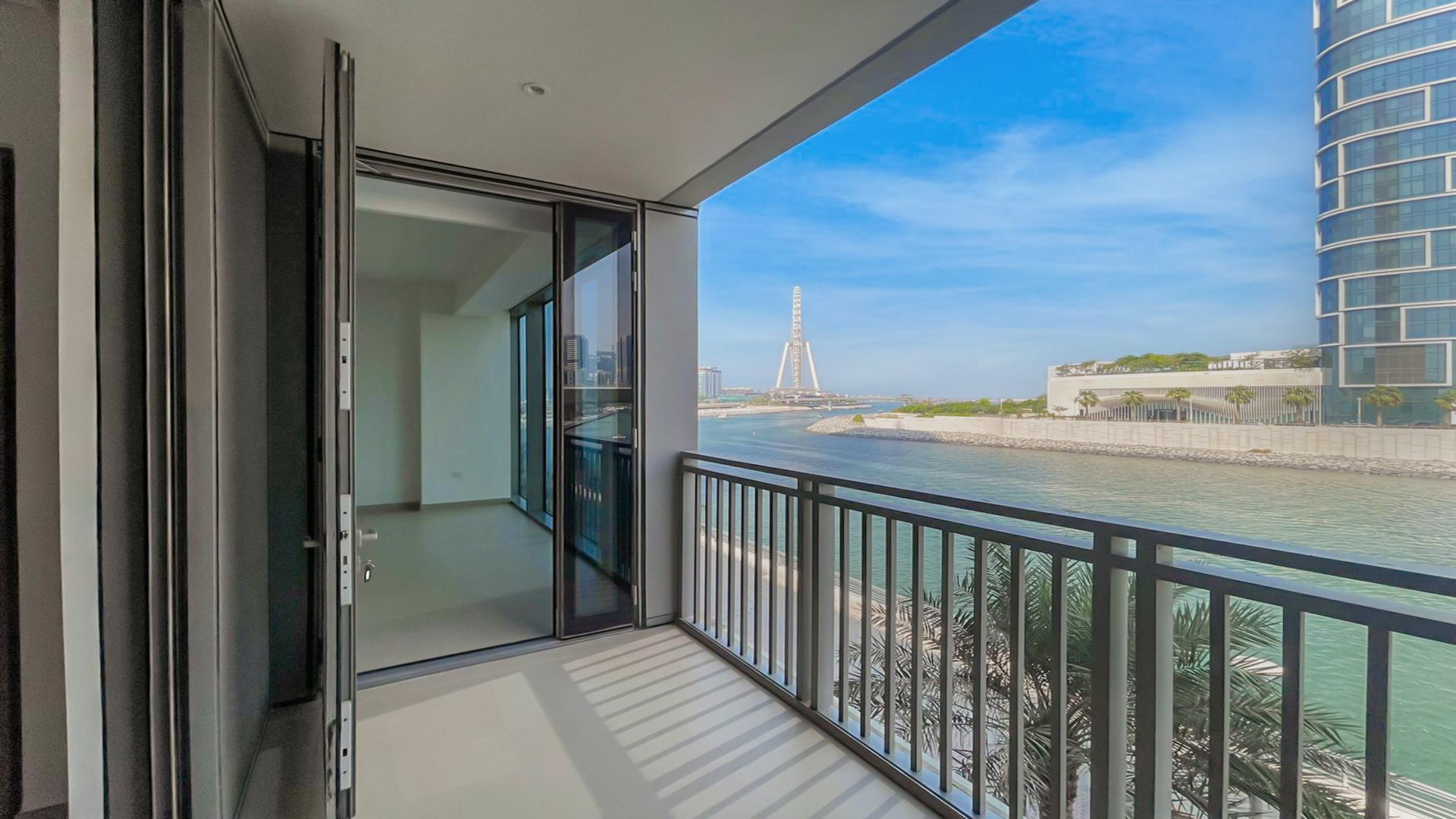 Empty living area in luxury Dubai Marina apartment with modern kitchen and balcony access