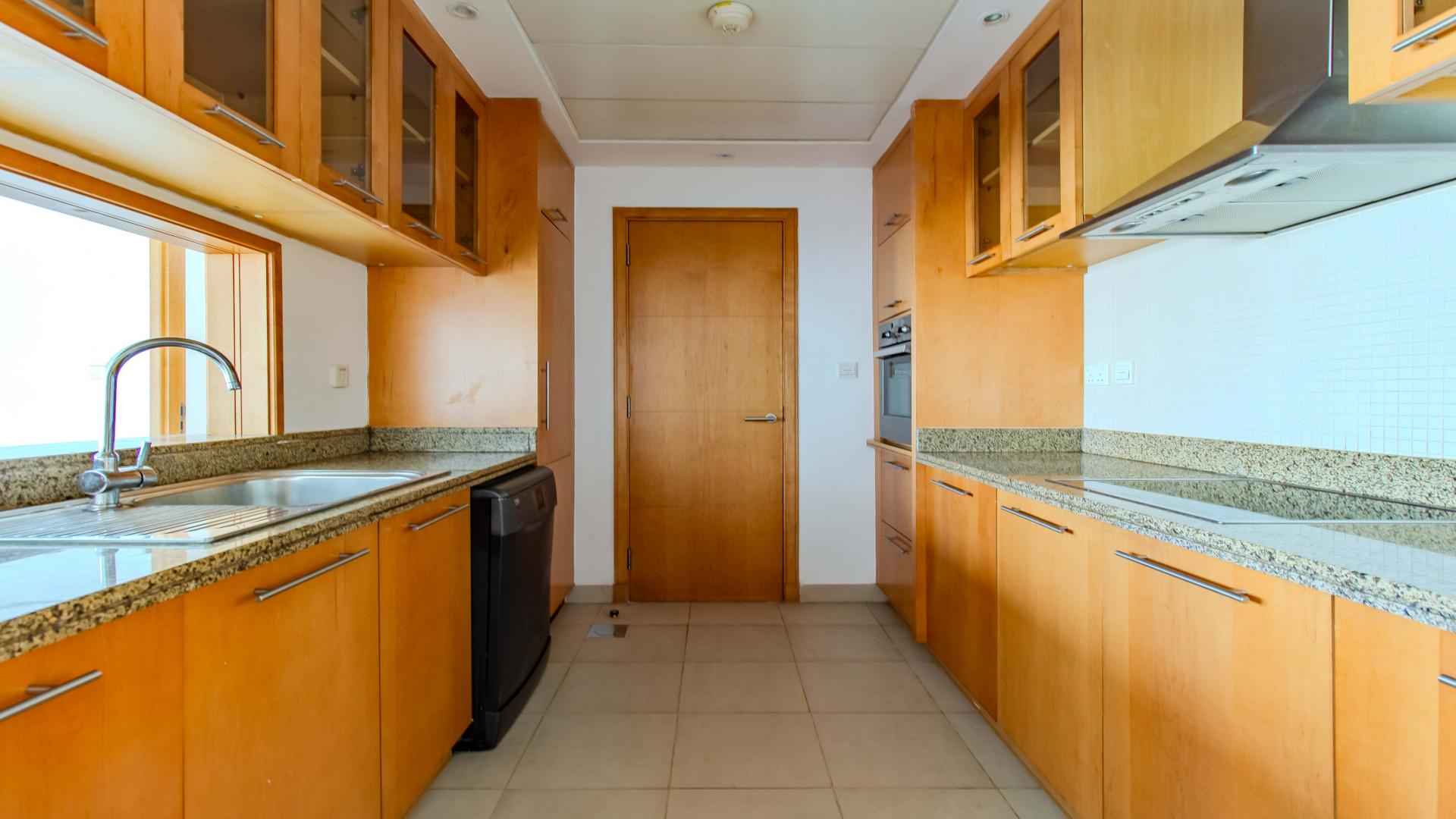 "Spacious Dubai Marina apartment interior with tiled flooring and open kitchen layout for rent.",Modern kitchen with granite countertops in Dubai Marina apartment for rent, LP39549