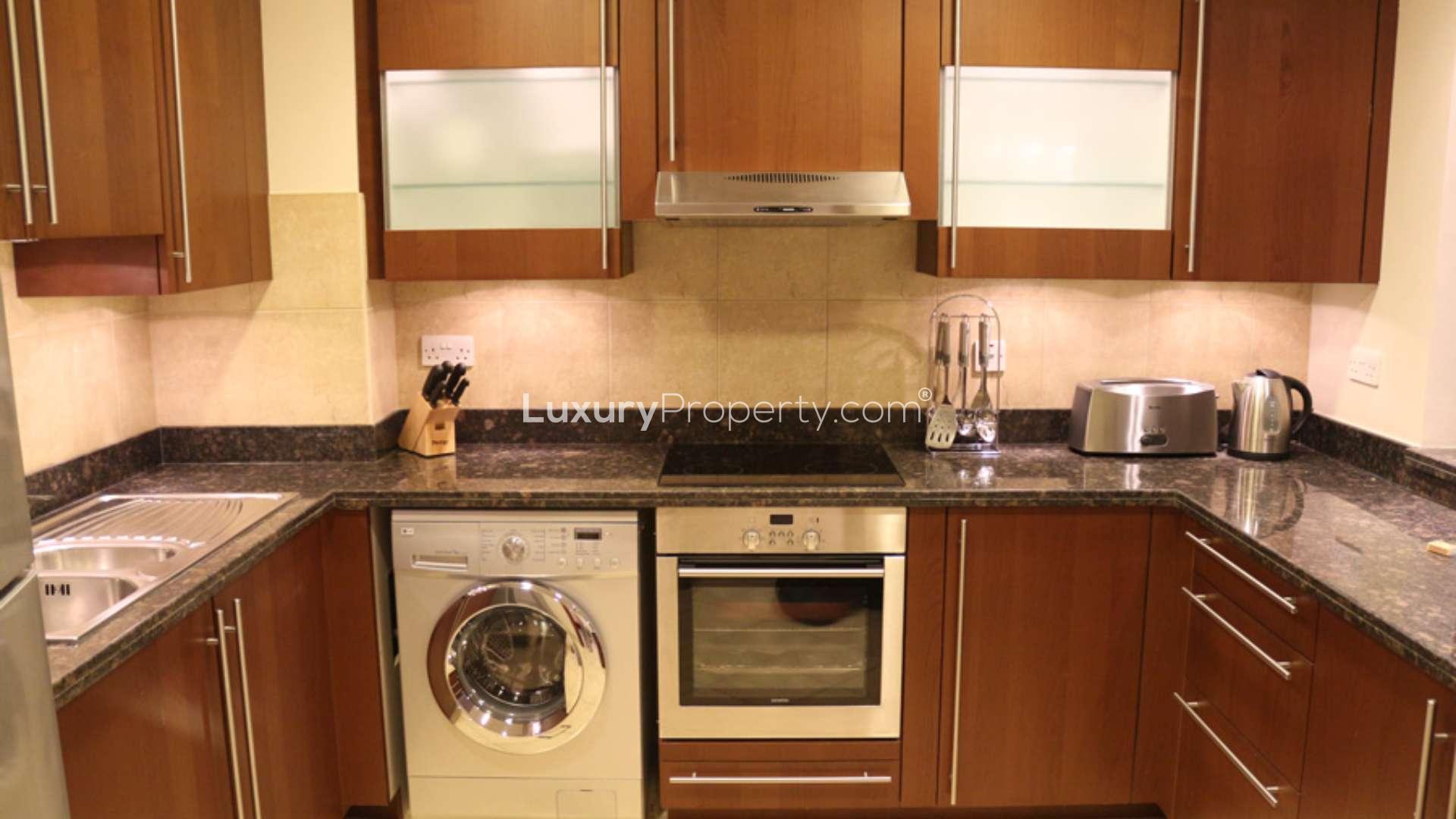 "Balcony view from Palm Jumeirah apartment overlooking sea and modern architecture on Golden Mile.",Modern kitchen in 1-bedroom Palm Jumeirah apartment, featuring wood cabinets and granite countertops