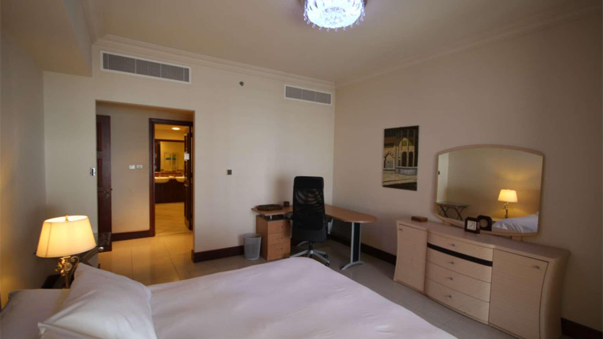 Stunning Palm Jumeirah apartment bedroom with modern decor, desk, and warm lighting