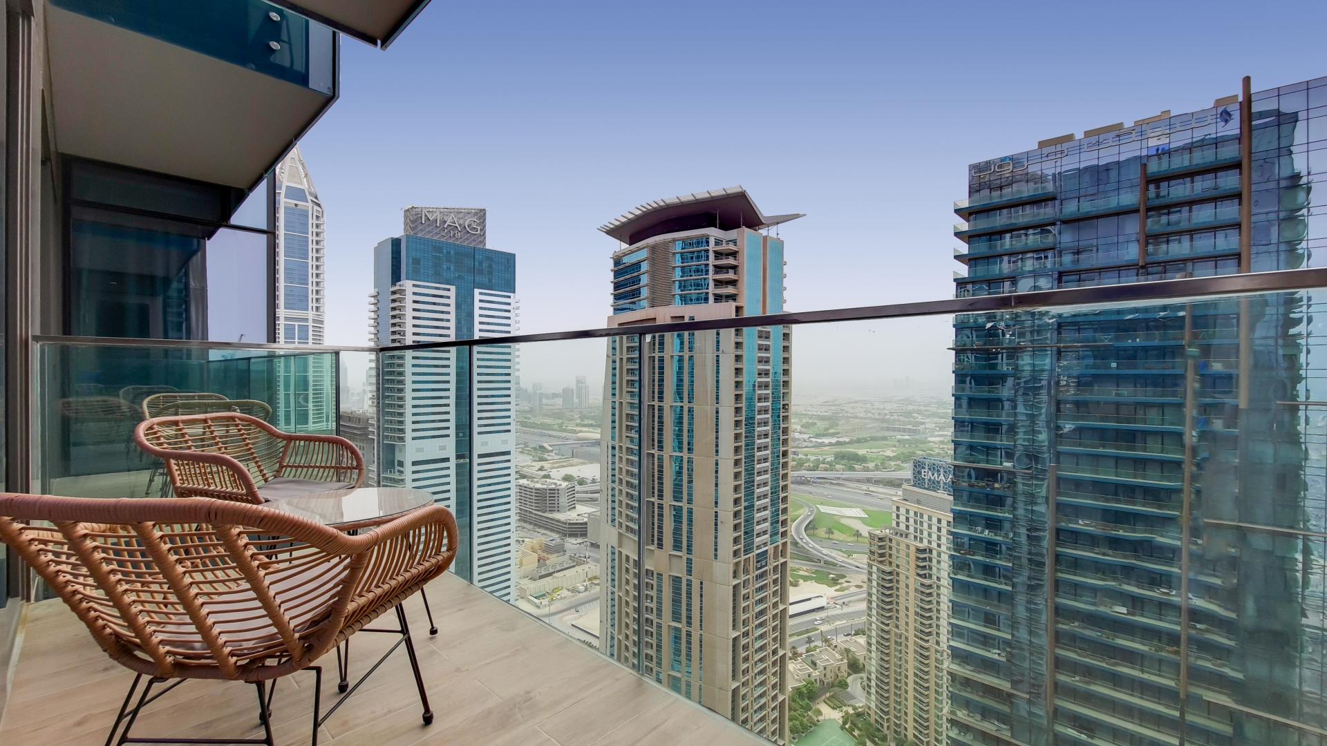 Modern living room with marina views, glass table, and TV in Dubai Marina apartment