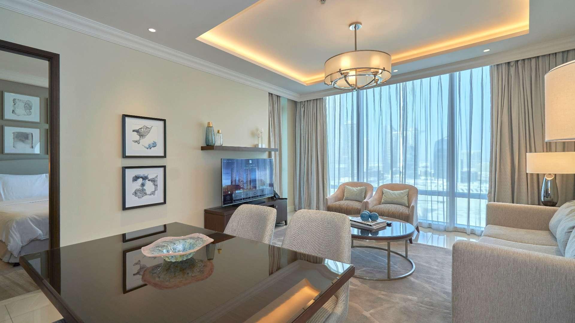 Alt text: "Downtown Dubai skyline view from one-bed apartment, includes Burj Khalifa and Fountain Views.",Fully furnished living room in Downtown Dubai apartment with Burj Khalifa view