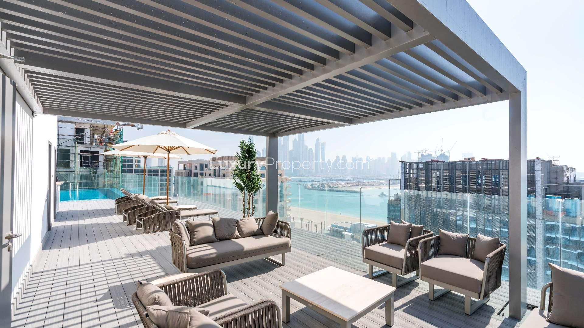 "Spacious balcony with ocean view in modern Palm Jumeirah apartment for rent.",Rooftop terrace with modern seating and sea views, Palm West Beach apartment rental