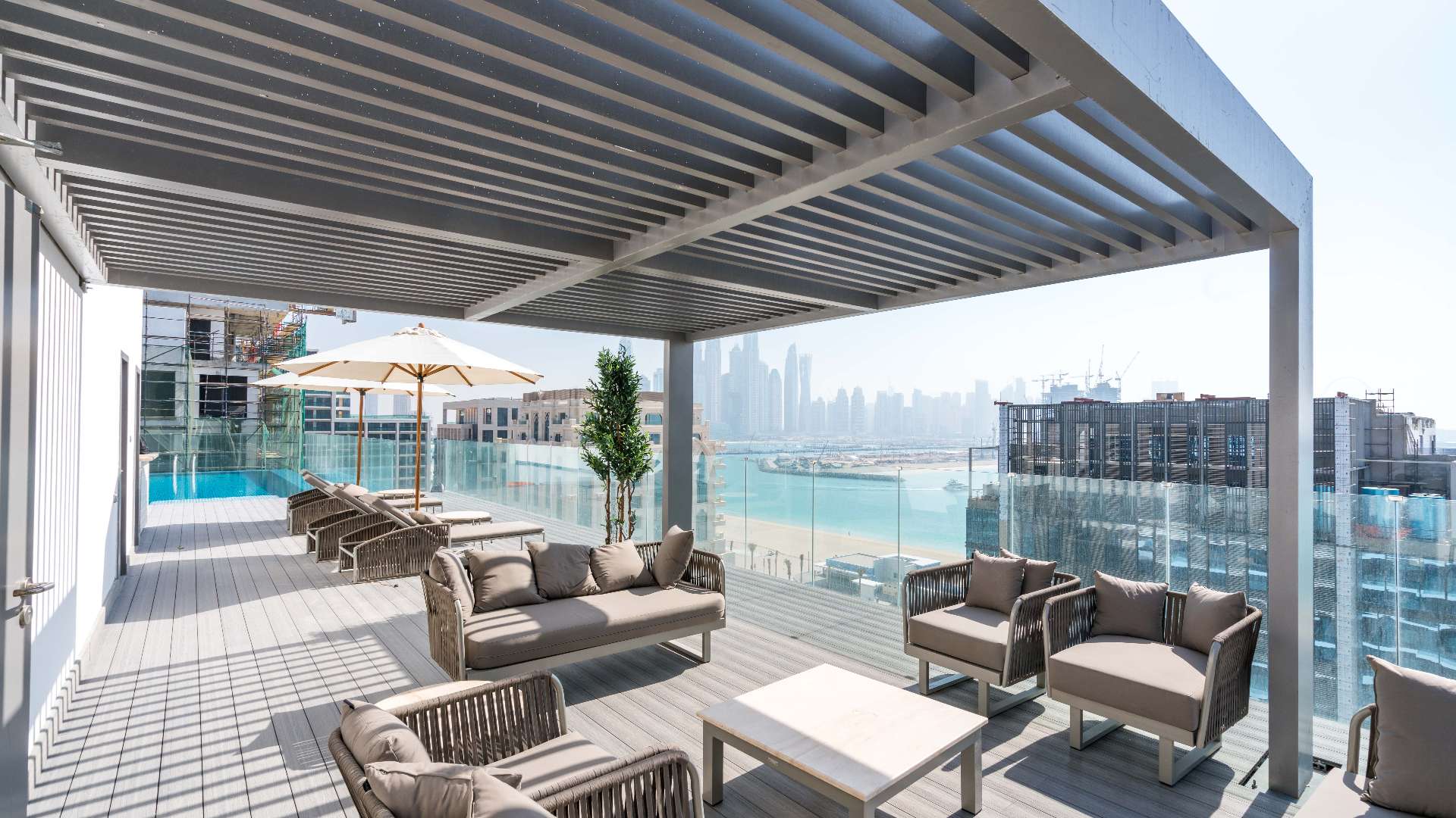 "Spacious balcony with ocean view in modern Palm Jumeirah apartment for rent.",Rooftop terrace with modern seating and sea views, Palm West Beach apartment rental