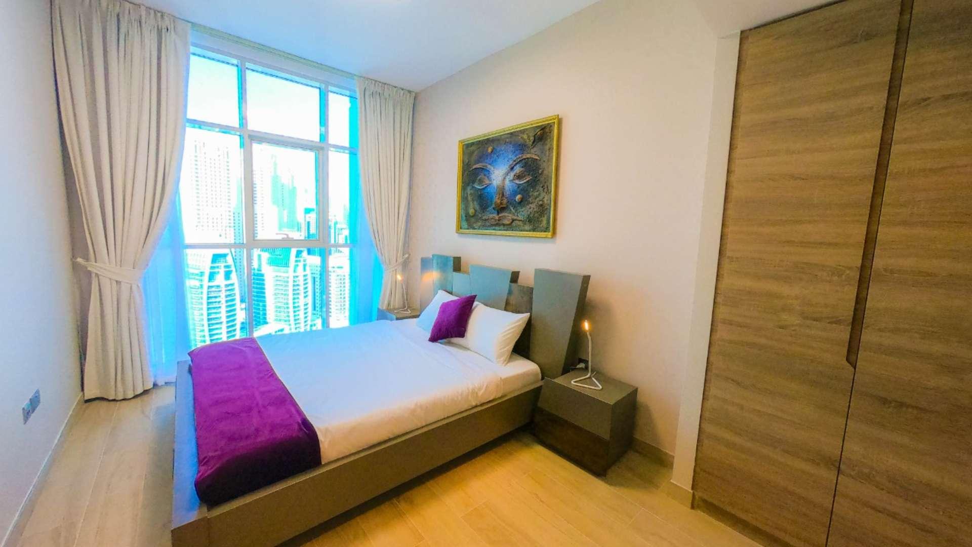 Modern furnished bedroom in Dubai Marina apartment, featuring en-suite bathroom and stylish decor
