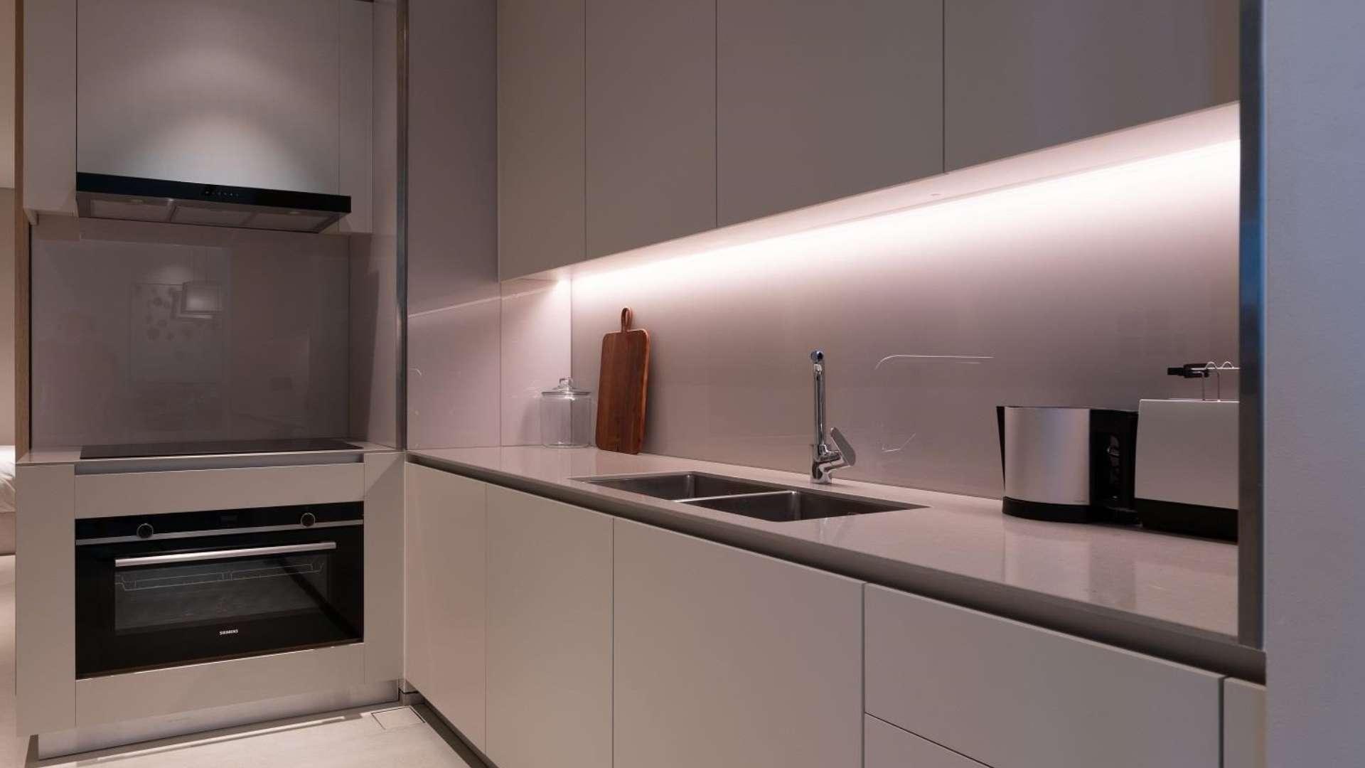 "Modern high-floor apartment interior in Jumeirah Beach Residence, featuring stylish living and dining area.",Modern kitchen in high-floor Jumeirah Beach Residence apartment, featuring sleek cabinetry and appliances