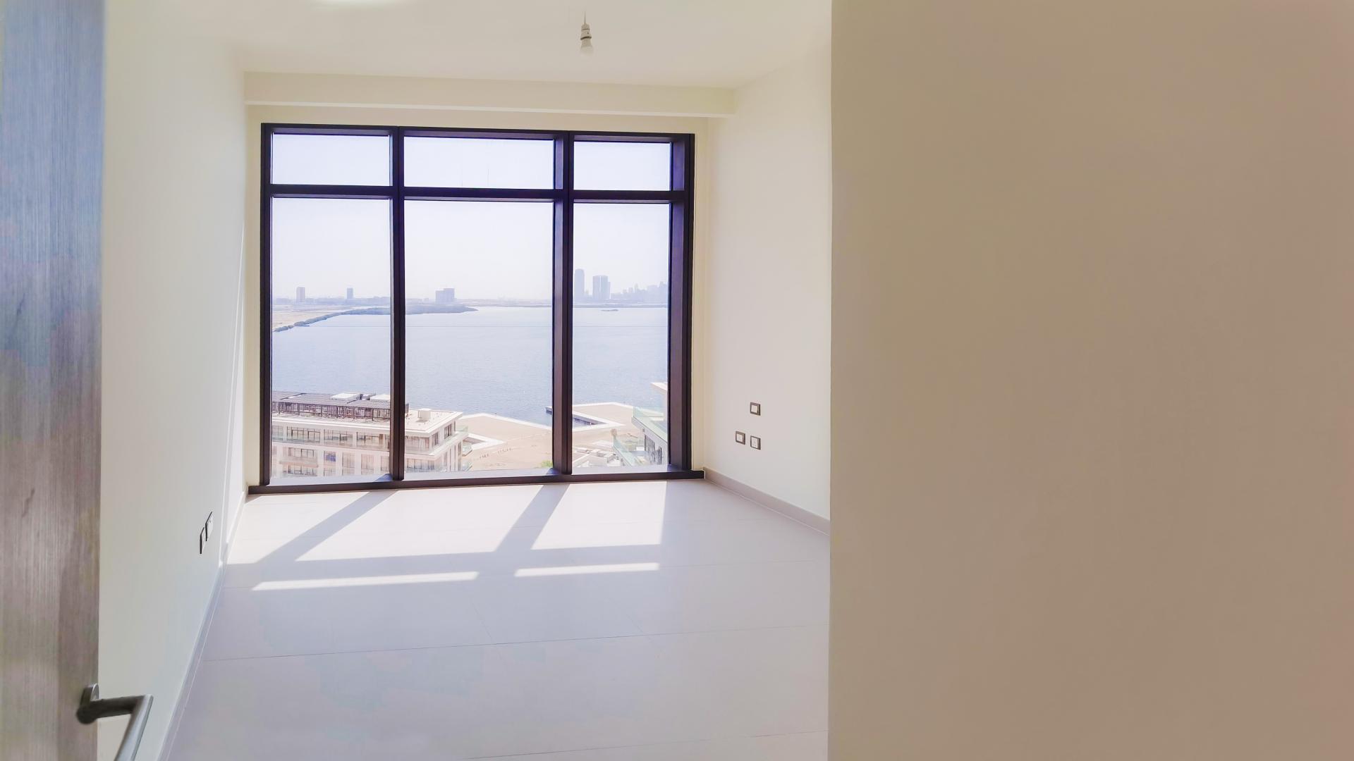 Modern living room with large windows in Dubai Creek Harbour apartment, The Cove