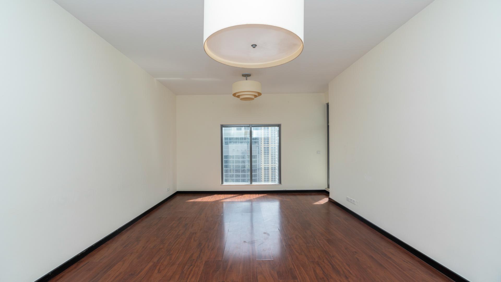 "Balcony view from 1-bed apartment in Green Lake Tower 2, JLT, overlooking cityscape.",Empty modern apartment room with wooden floors and window view in Green Lake Tower 2
