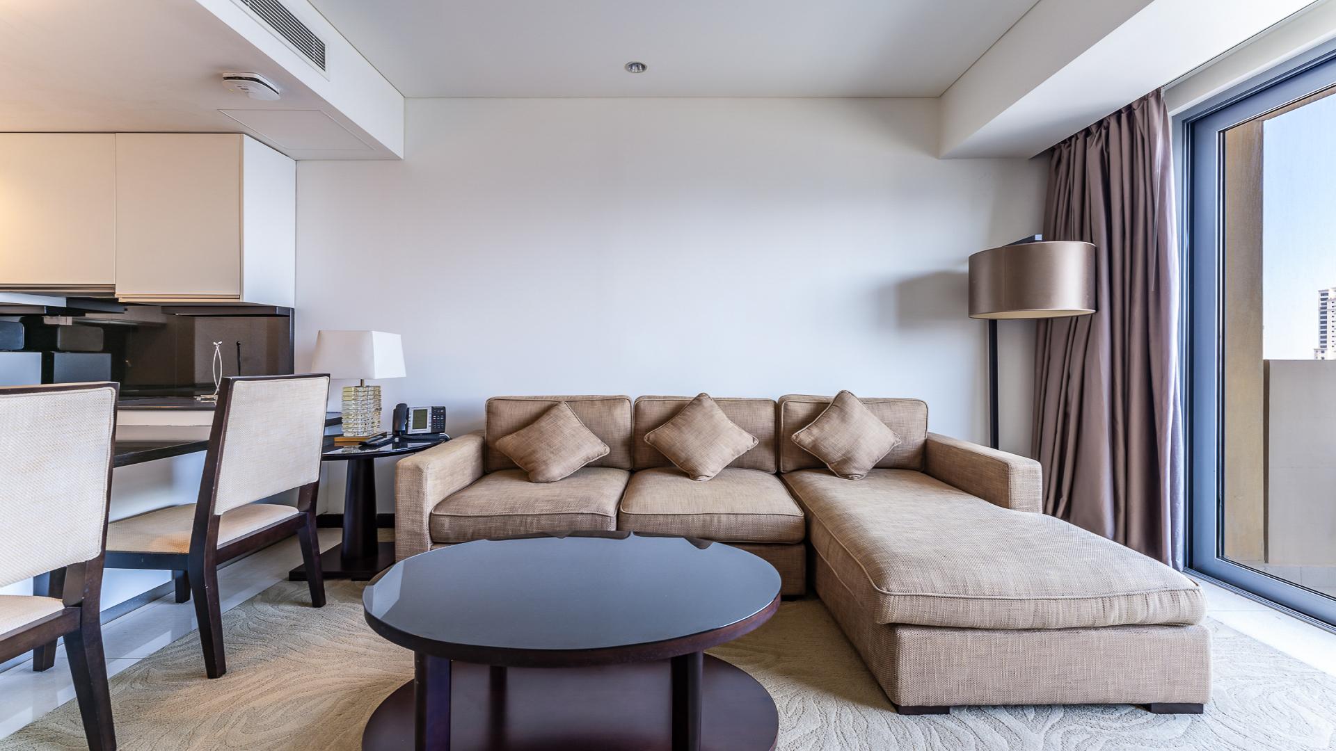 Modern living room in Dubai Marina apartment with beige sofa and large window view