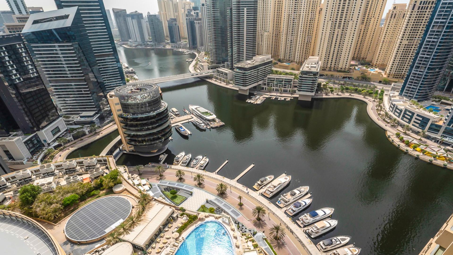 Modern living room in Dubai Marina apartment with sleek furnishings and open kitchen layout