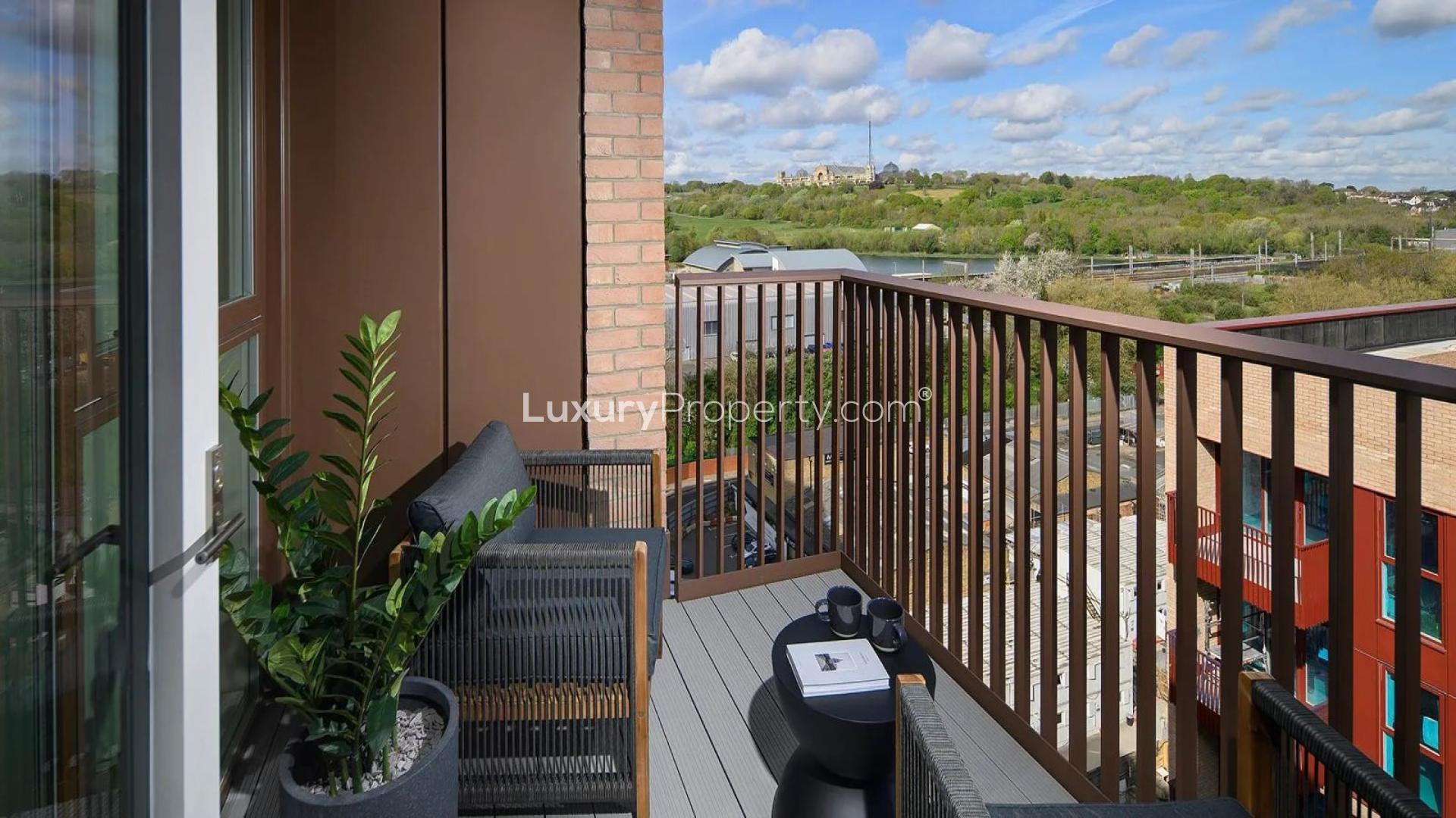 Modern apartment balcony view of Alexandra Palace, London, with outdoor seating and greenery