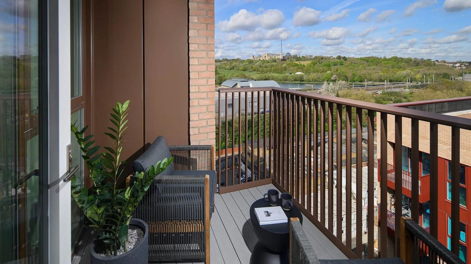 Modern apartment balcony view of Alexandra Palace, London, with outdoor seating and greenery