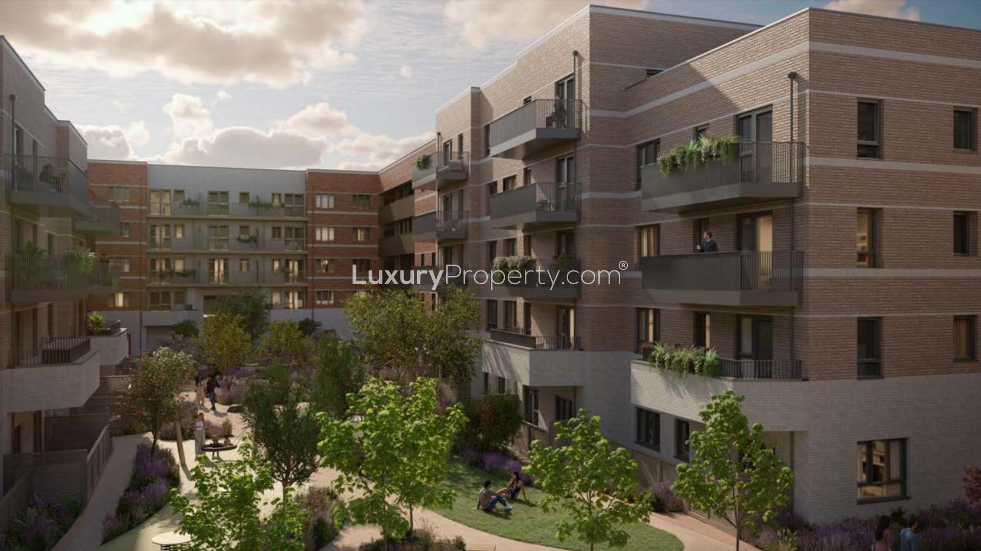 Modern London Square apartment living room with green sofa, artwork, and garden view