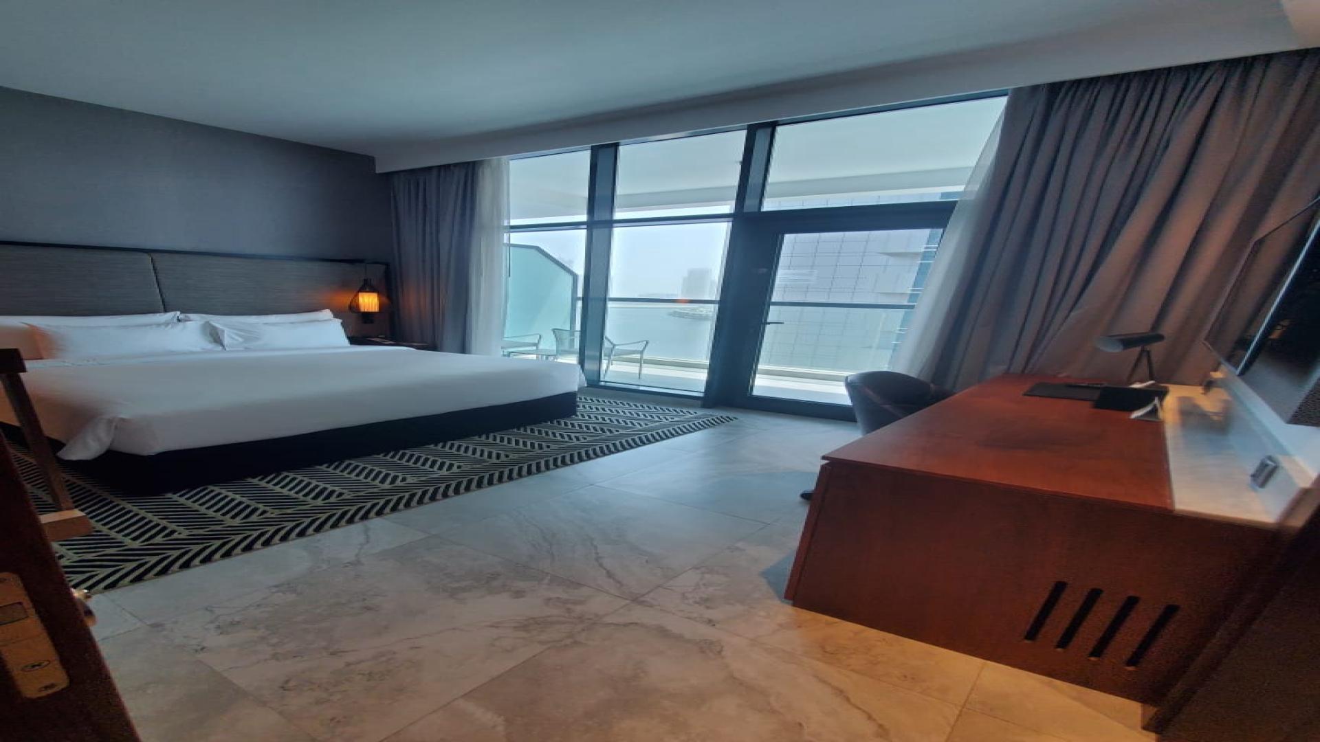 Modern bedroom in Business Bay apartment for sale, featuring large windows and sleek furnishings