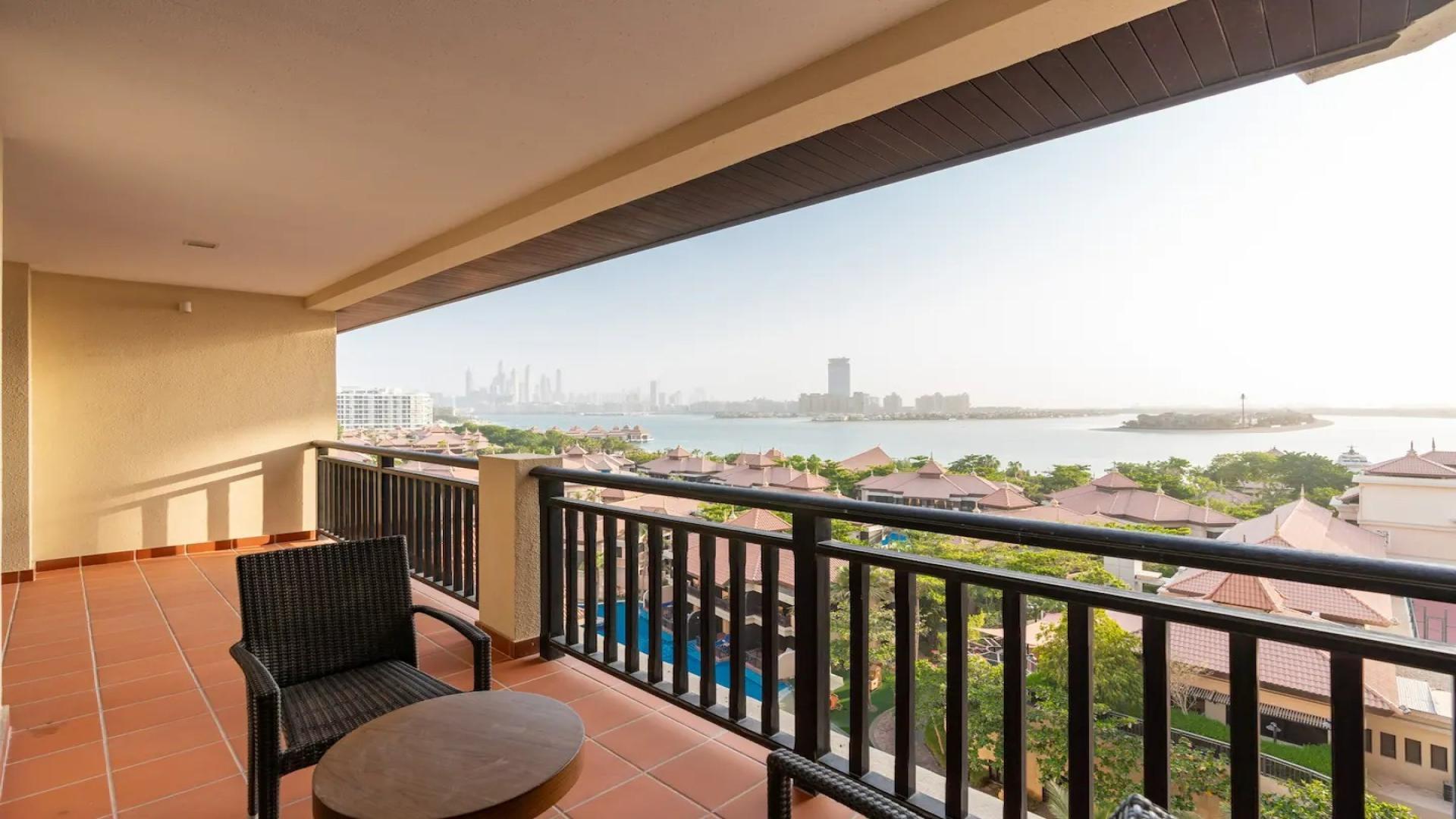 Furnished living room in Palm Jumeirah apartment, modern decor with green chairs and artwork