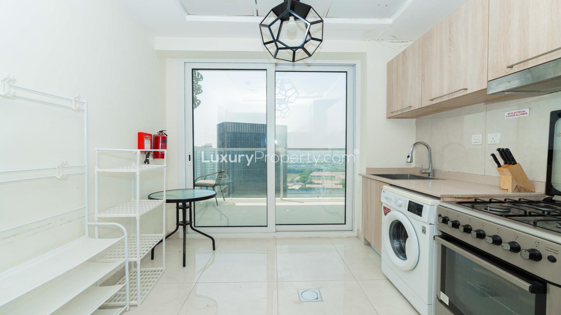 Alt text: "Modern furnished living room in one-bedroom AG Tower apartment, Business Bay, for sale.",Modern kitchen with appliances in fully furnished one-bedroom apartment, AG Tower, Business Bay