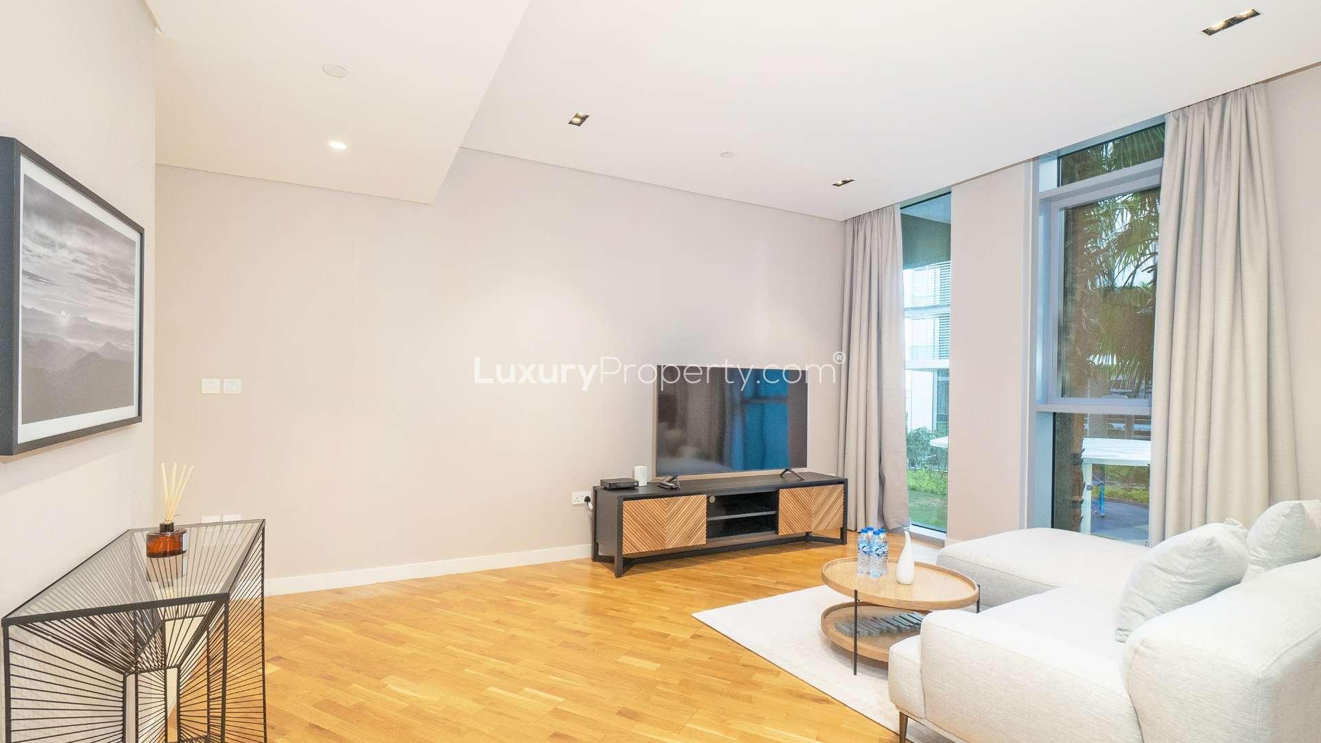 Living room in Bluewaters 1-bedroom apartment, modern decor, large windows, hardwood floors