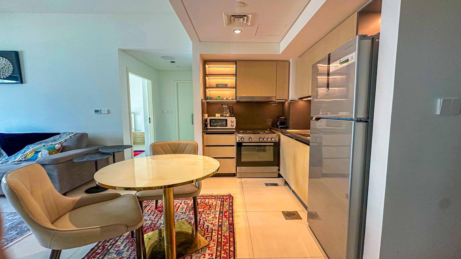 Alt text: "Downtown Dubai apartment pool view, Burj Crown, high-rise skyline, fully furnished, for sale.",Modern furnished kitchen and dining area in Burj Crown apartment, Downtown Dubai