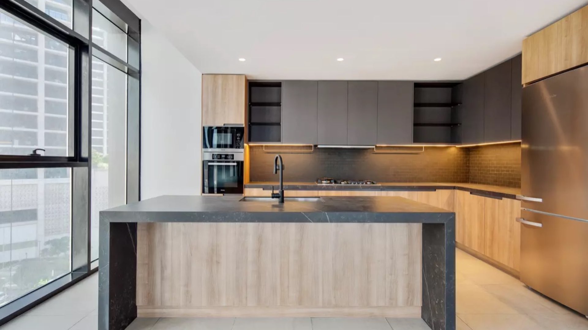 "Spacious DT1 apartment with large windows overlooking Downtown Dubai skyline, available for sale.",Modern kitchen in DT1 Tower apartment, Downtown Dubai, featuring sleek cabinetry and appliances