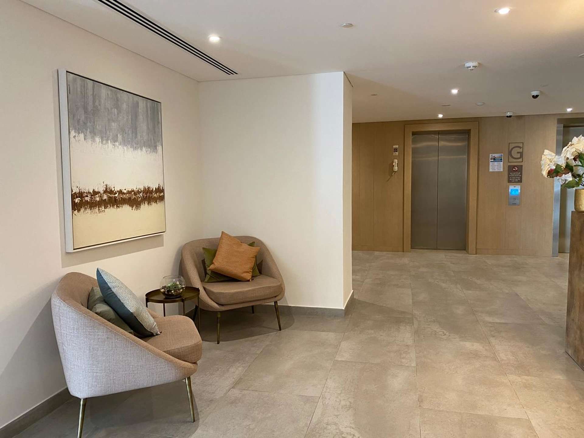 Lobby area of Eaton Place apartment, Jumeirah Village Circle, with modern seating and elevator