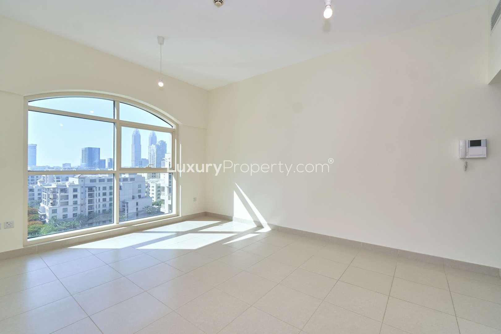 "Spacious balcony view from 1-bedroom apartment in Mosela Tower, The Views, Dubai.",Bright living room with large window, city views in 1-bedroom Mosela Tower apartment, Dubai
