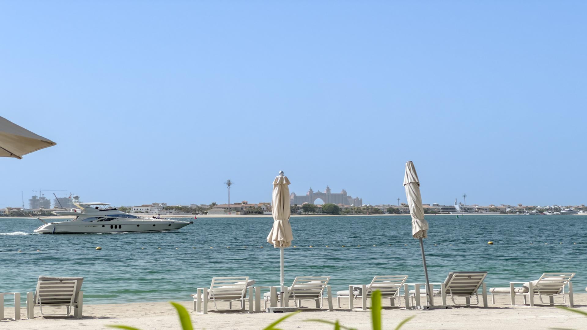 Beachfront view from Sunrise Bay apartment, Dubai Harbour, showcasing Palm Jumeirah and luxury yacht