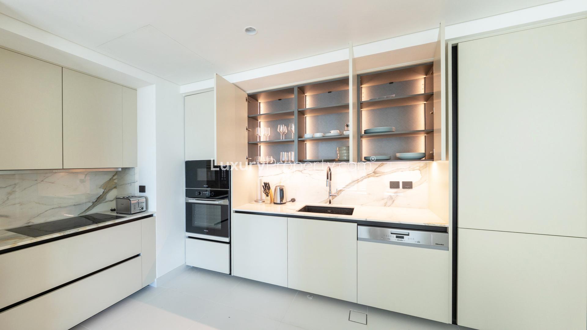 "Spacious balcony view overlooking Dubai Harbour skyline and marina at Emaar Beachfront apartment.",Modern kitchen in 1-bedroom apartment, Emaar Beachfront, Dubai Harbour, with sleek cabinetry and appliances
