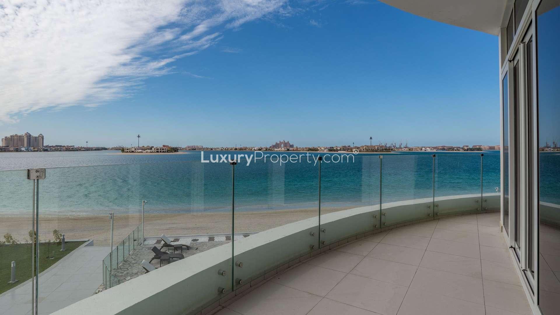 "Luxurious beachfront pool view from Royal Bay apartment, Palm Jumeirah, for sale.",Apartment balcony view of skyline over water in Royal Bay, Palm Jumeirah