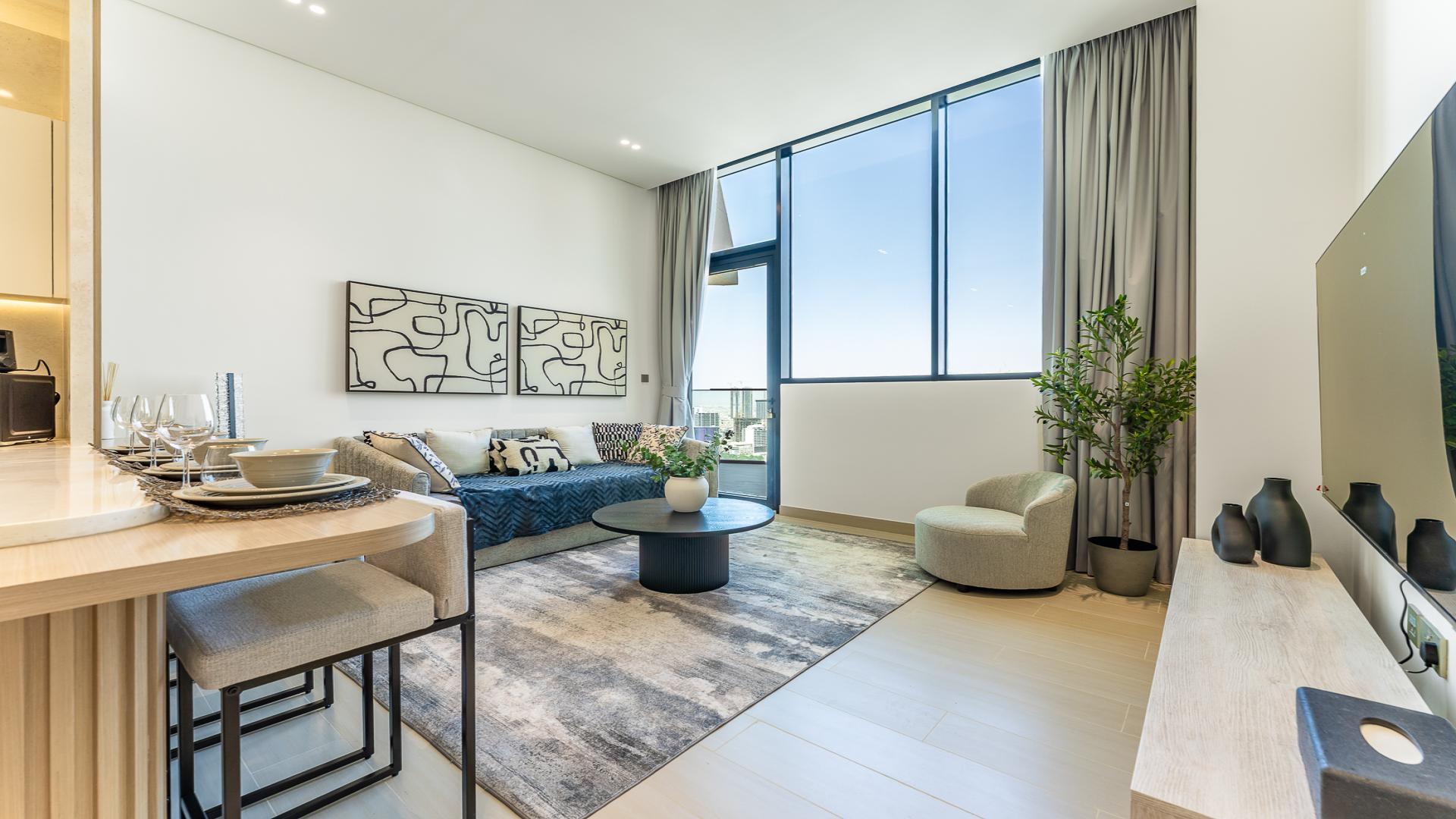 Modern open-plan living room and kitchen in Jumeirah Village Circle apartment, District 18