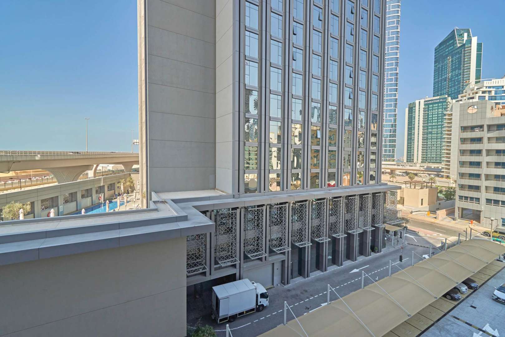 "Balcony view from luxury hotel room in TFG Marina Hotel, Dubai Marina for sale.","Exterior view of TFG Marina Hotel in Dubai Marina, showcasing modern architecture and surroundings.",Luxury one-bedroom apartment interior at TFG Marina Hotel, Dubai Marina for sale