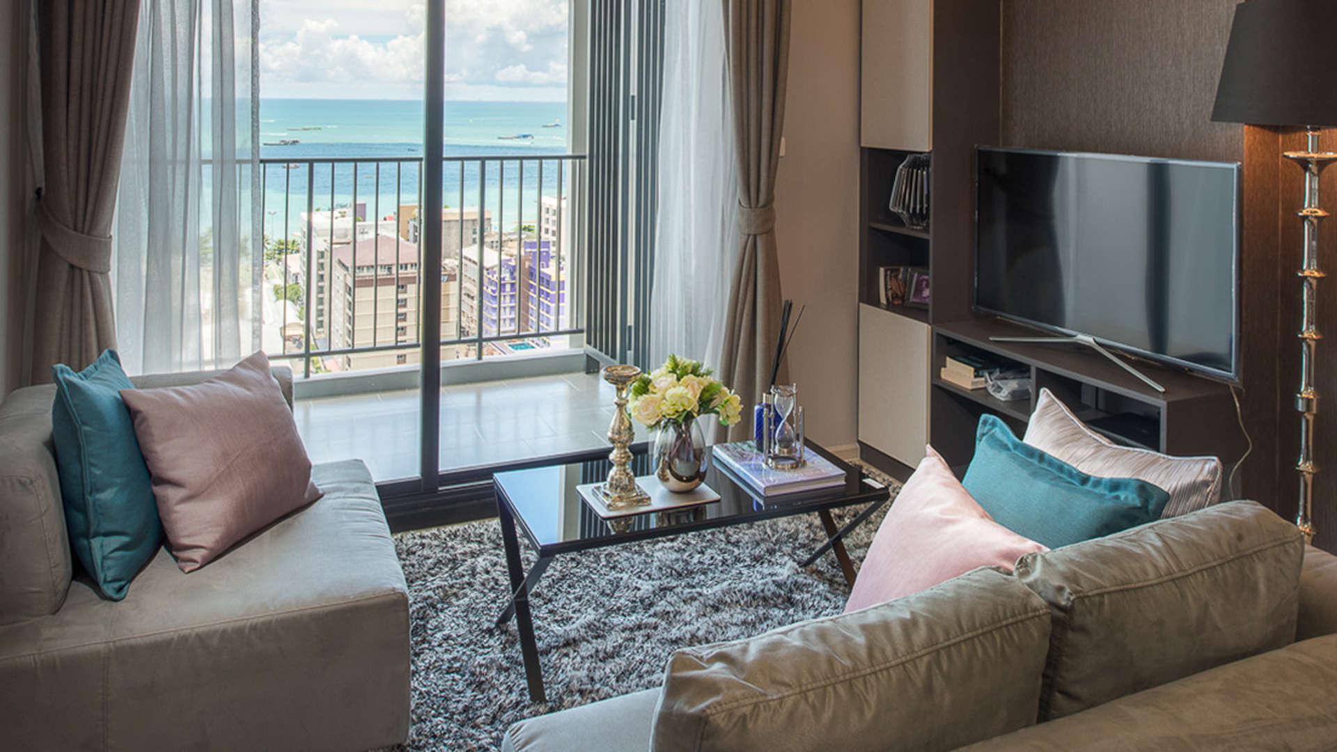 Modern apartment exterior at The Base, Pattaya, Thailand, featuring sleek glass facade and lighting