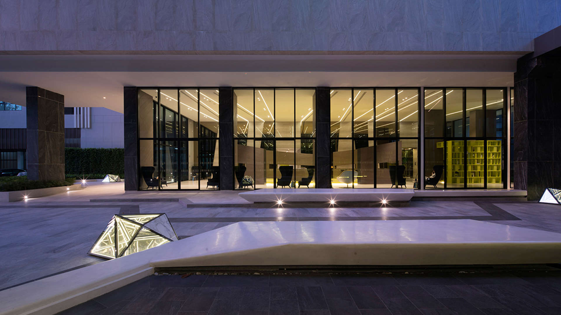 Modern apartment exterior at The Base, Pattaya, Thailand, featuring illuminated landscape and entrance