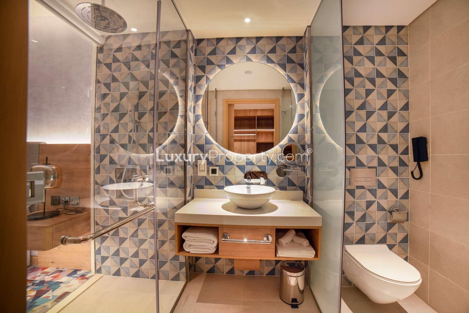 "Luxury balcony view of Dubai skyline at sunset, NH Collection Dubai The Palm apartment.",Modern bathroom with geometric tiles in NH Dubai The Palm apartment, Palm Jumeirah
