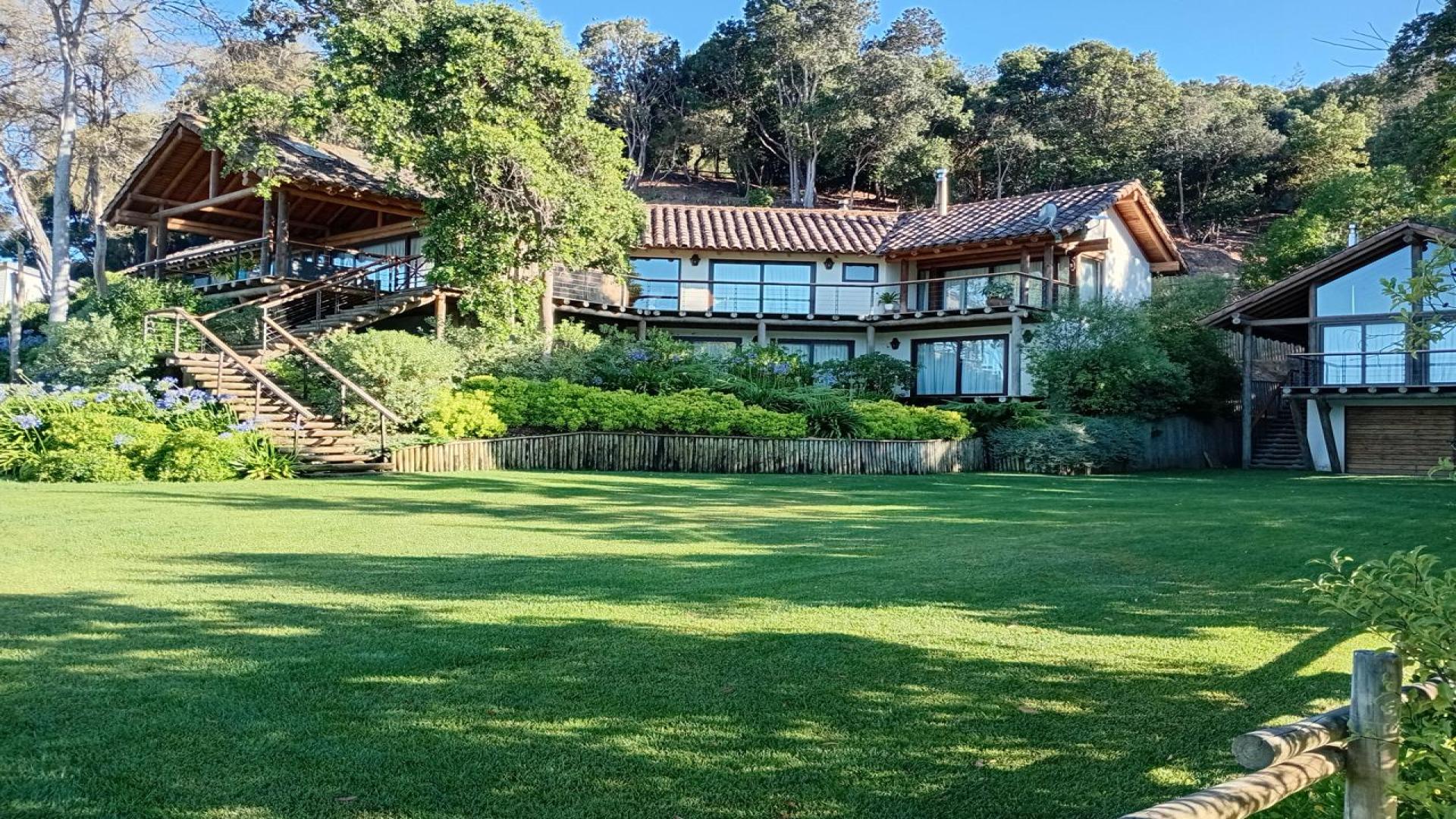 Lakefront property with lush greenery and wooden cabin at Lake Vichuquén, Curico Province