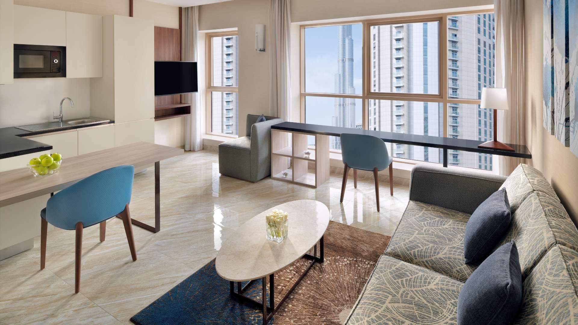 Contemporary serviced apartment living area with kitchen, TV, and sofa near Dubai Mall