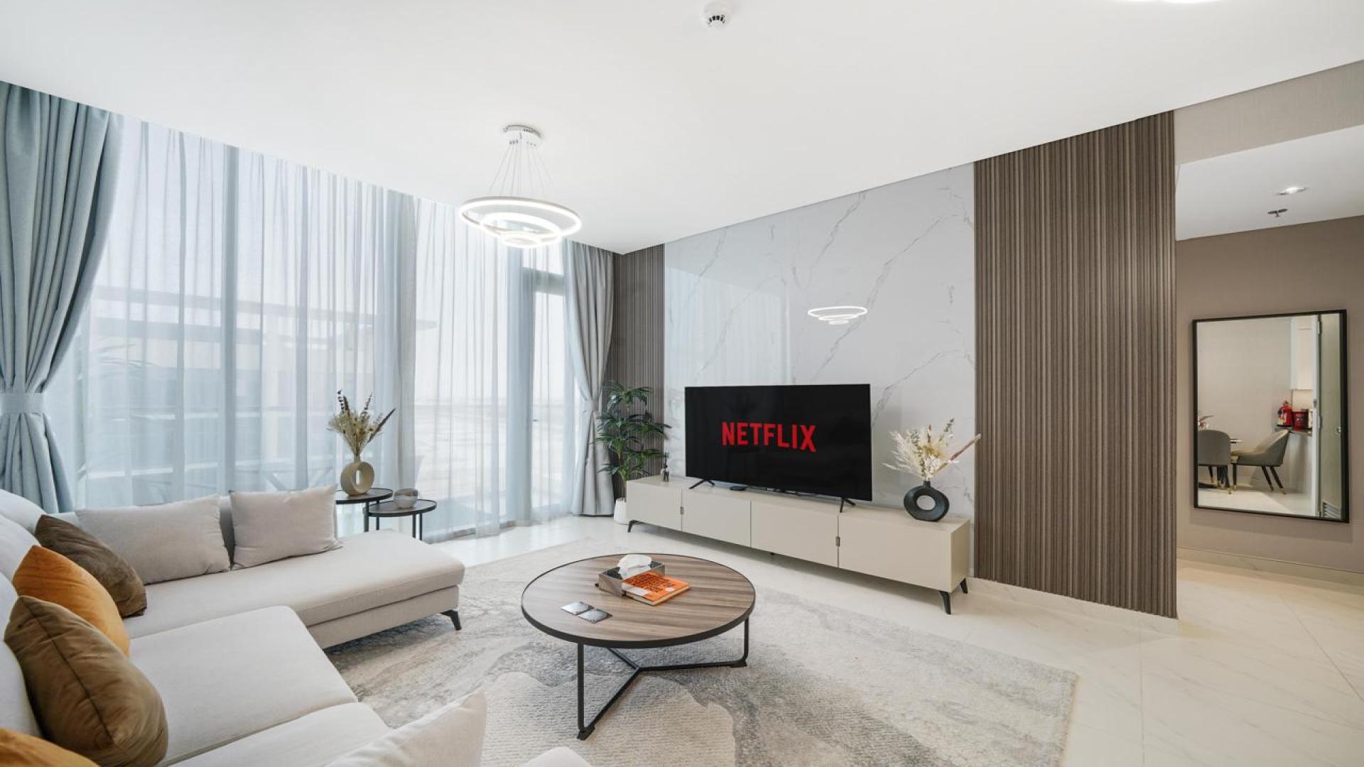 "Modern living room with white sofa, open kitchen in District One apartment, Mohammed Bin Rashid City.",Modern living room in District One apartment with stylish decor and natural light