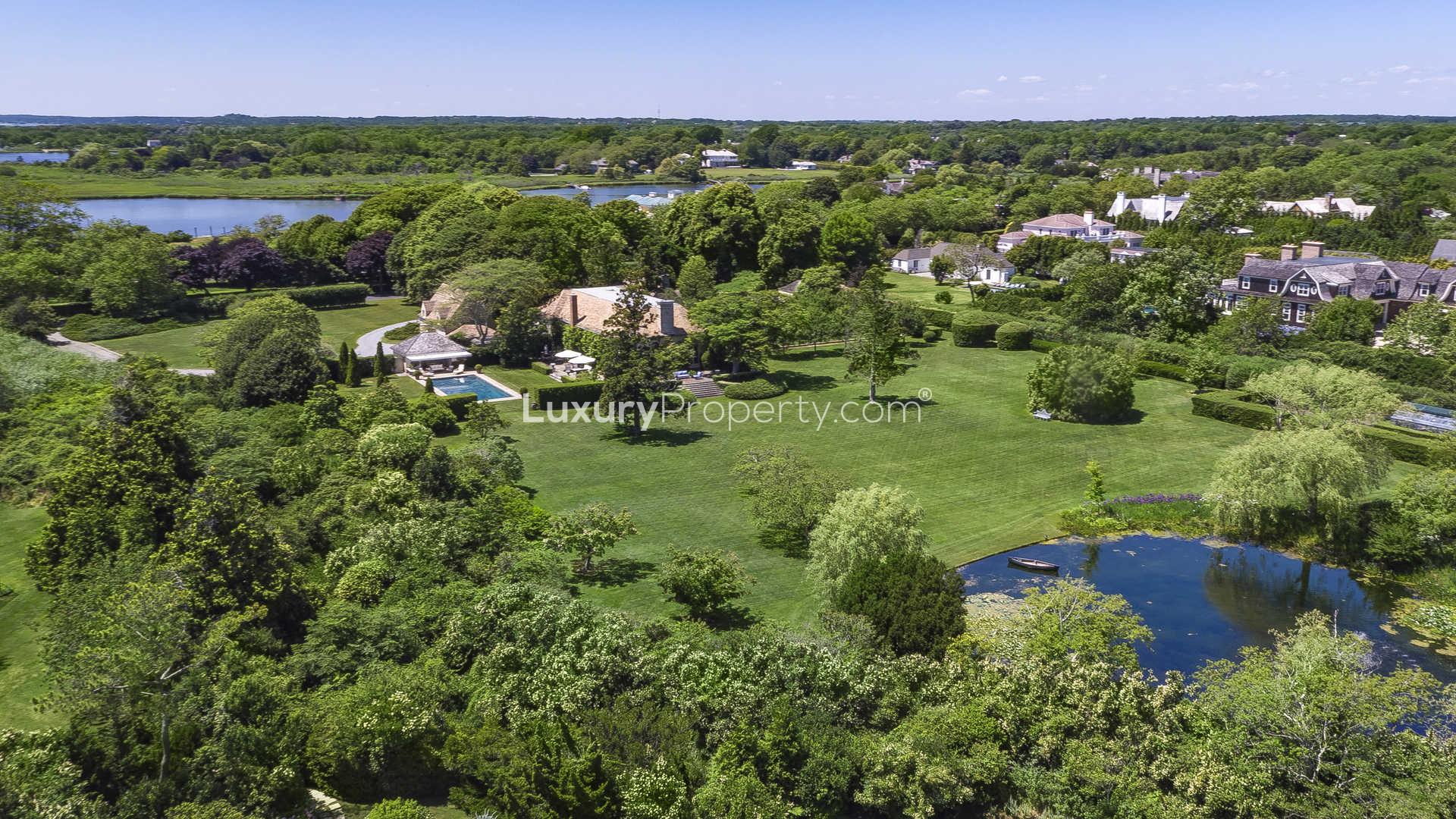 "French-style villa entrance with tree-lined driveway in Southampton, Hamptons, New York.",Aerial view of luxurious French-style villa with pool in Southampton's Hamptons community