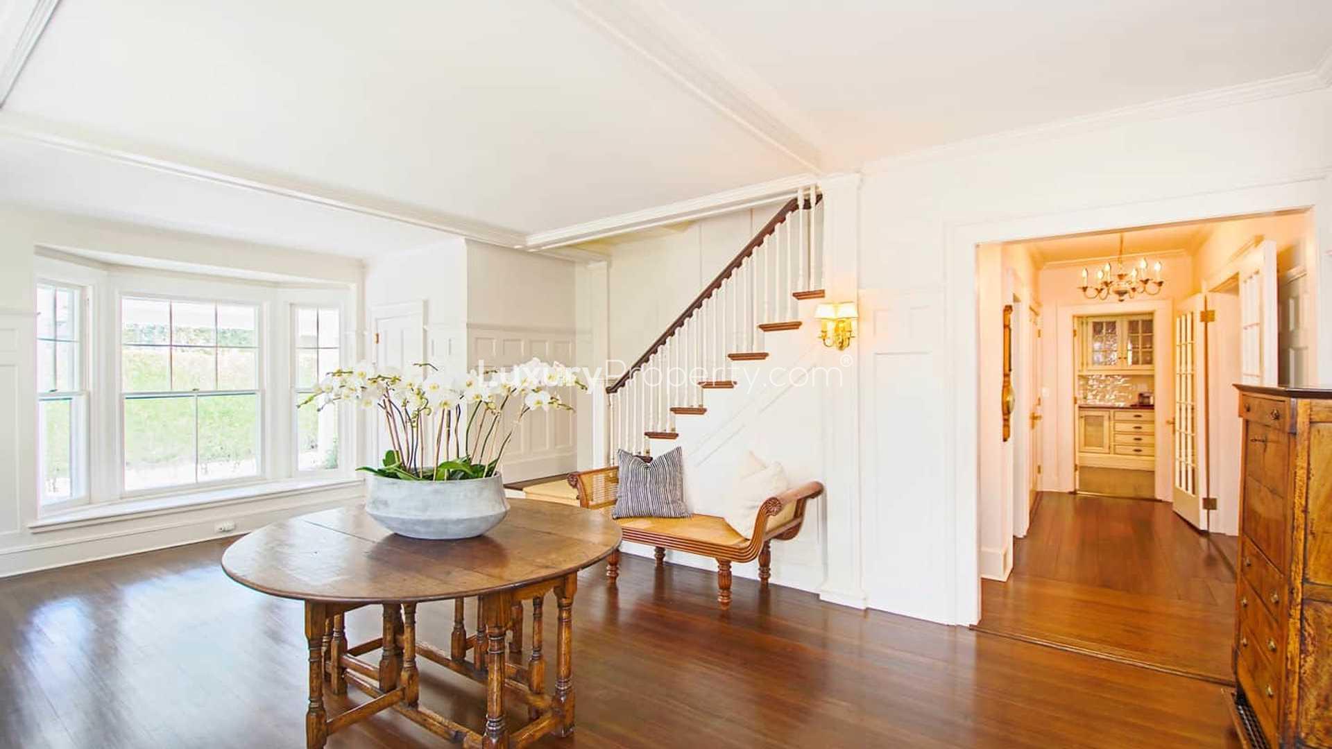 "19th-century Hamptons villa for sale, 10 bedrooms, lush garden, elegant architecture.",Elegant entryway of historic Hamptons villa with staircase and wooden furnishings, LP01229