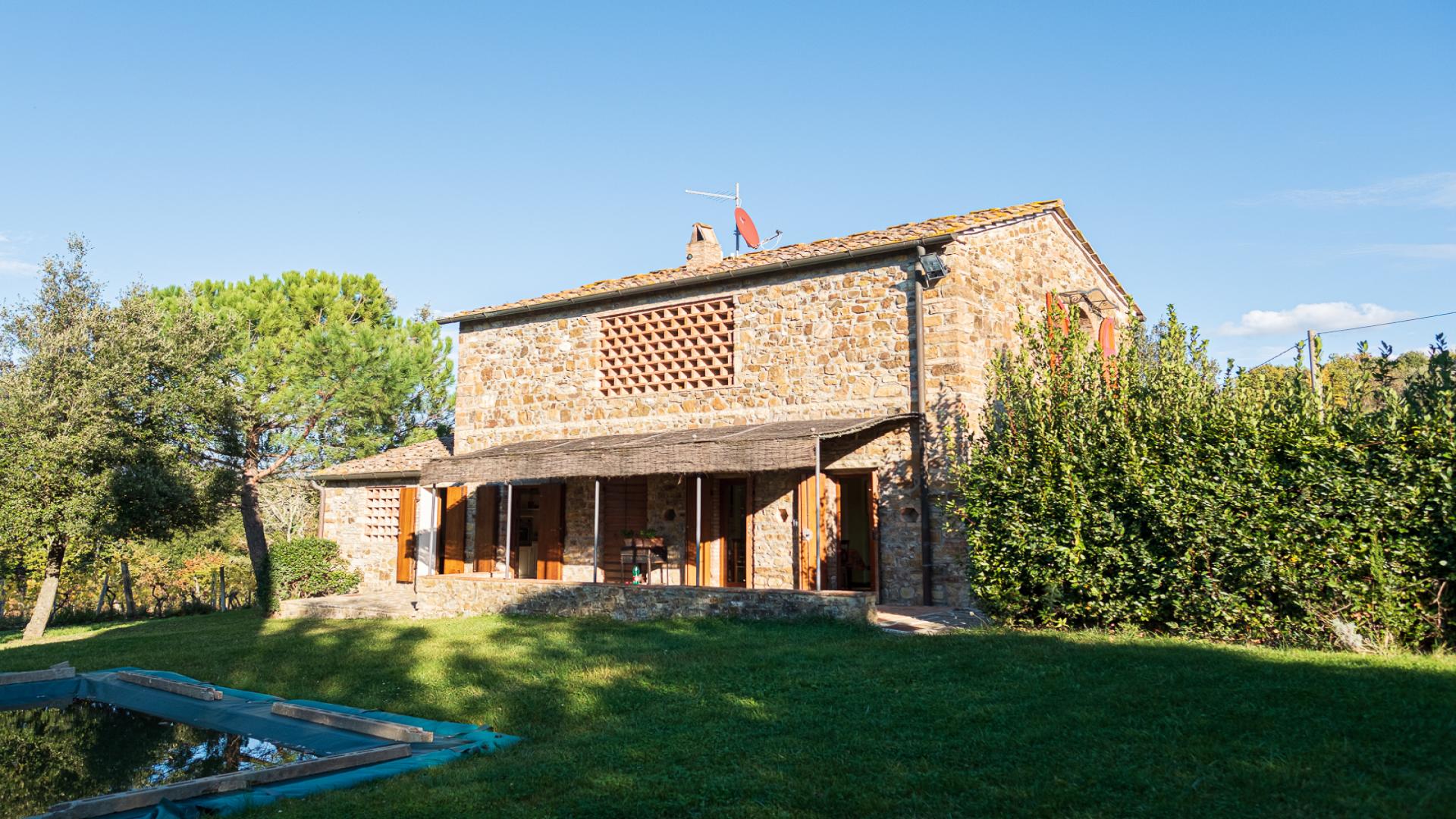 Rustic stone villa exterior in Tenuta Chianti Classico, Florence, surrounded by greenery