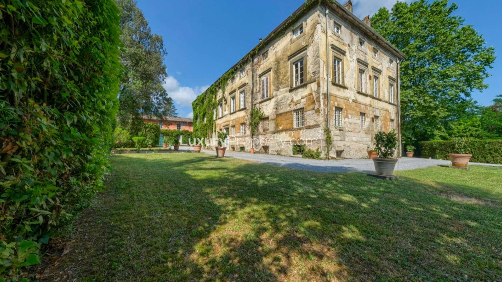 "Charming Lucca Aristocratic Manor Villa with lush ivy facade, gravel courtyard, for sale.",Lucca Aristocratic Manor villa exterior view with lush garden and historic architecture