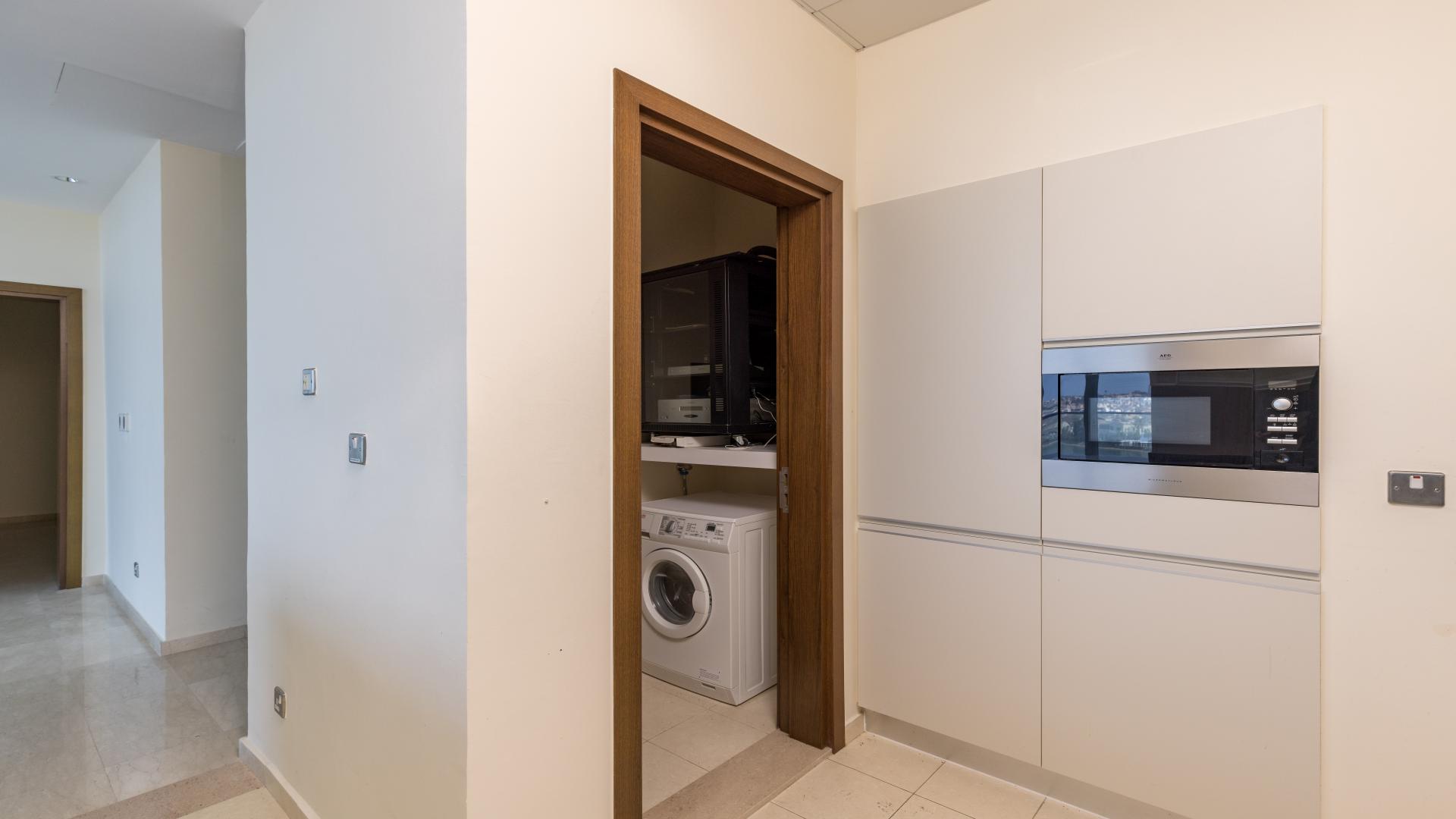 Modern kitchen with built-in appliances and laundry area in Oceana apartment, Palm Jumeirah