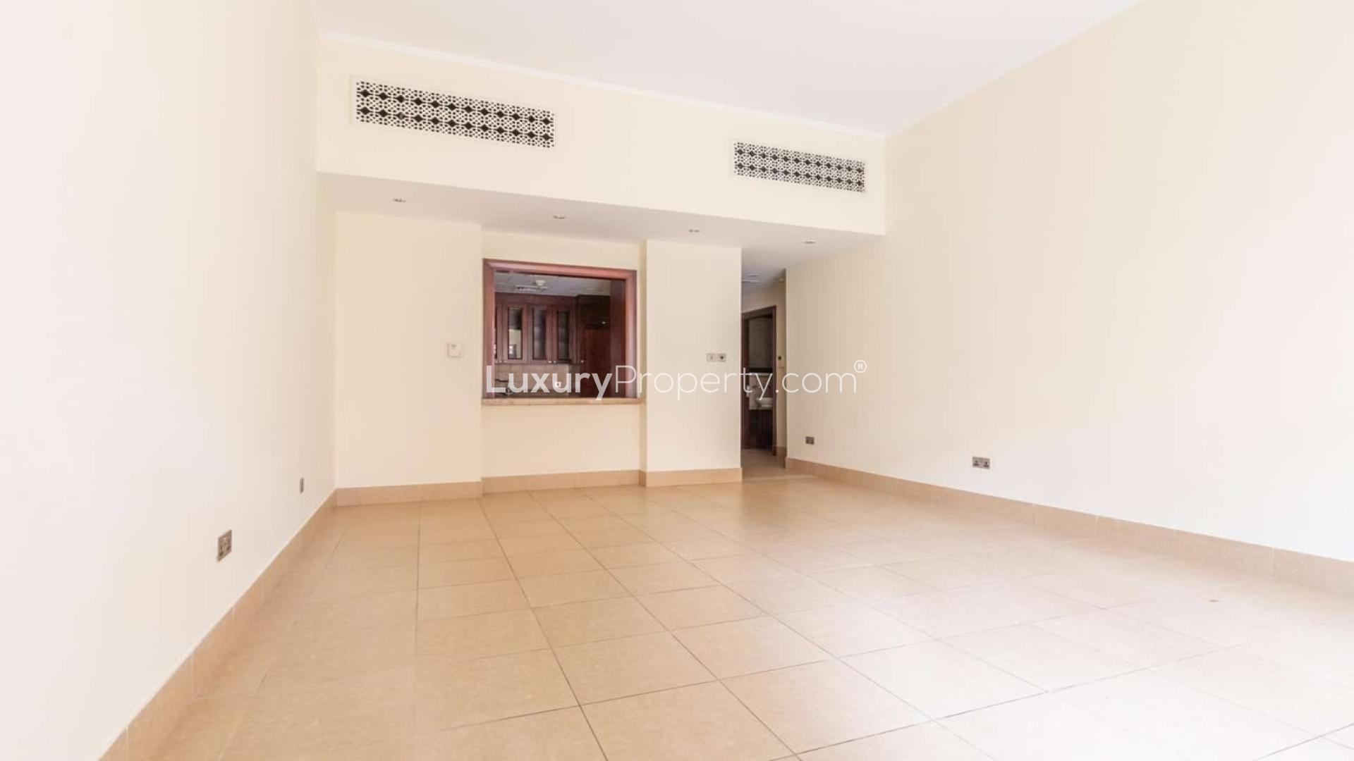 Empty living room in Miska apartment, Old Town, Dubai, with tiled flooring and garden access