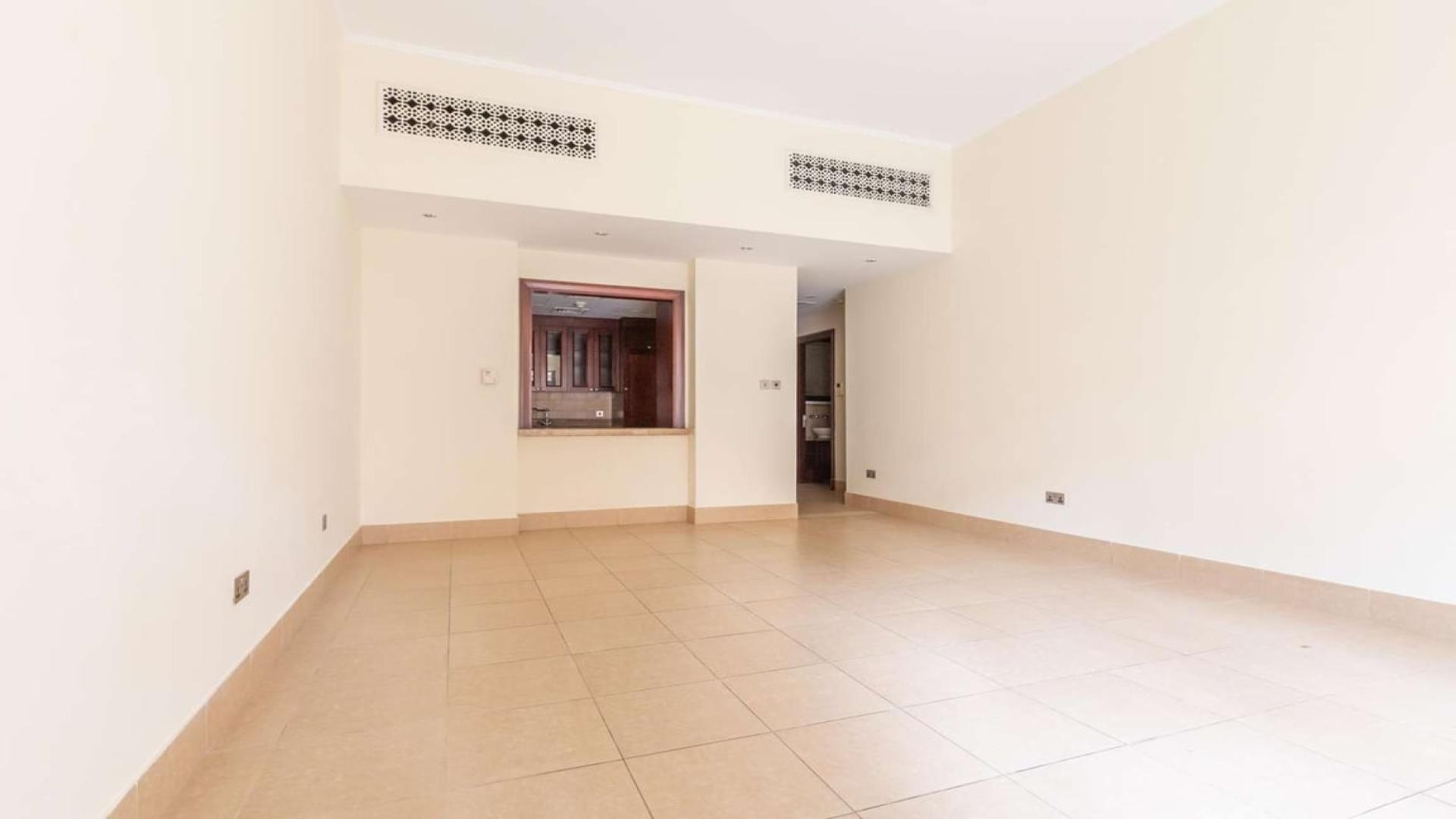 Empty living room in Miska apartment, Old Town, Dubai, with tiled flooring and garden access