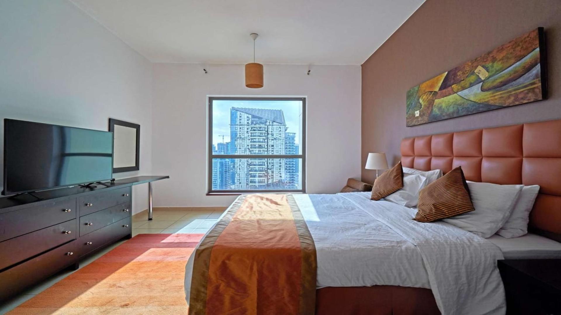 "Stunning high-rise view of JBR waterfront and cityscape from Shams apartment for rent.","Modern bedroom with city view in beachfront apartment, Shams, Jumeirah Beach Residence, Dubai.",Modern living room and dining area in beachfront JBR apartment for rent at Shams